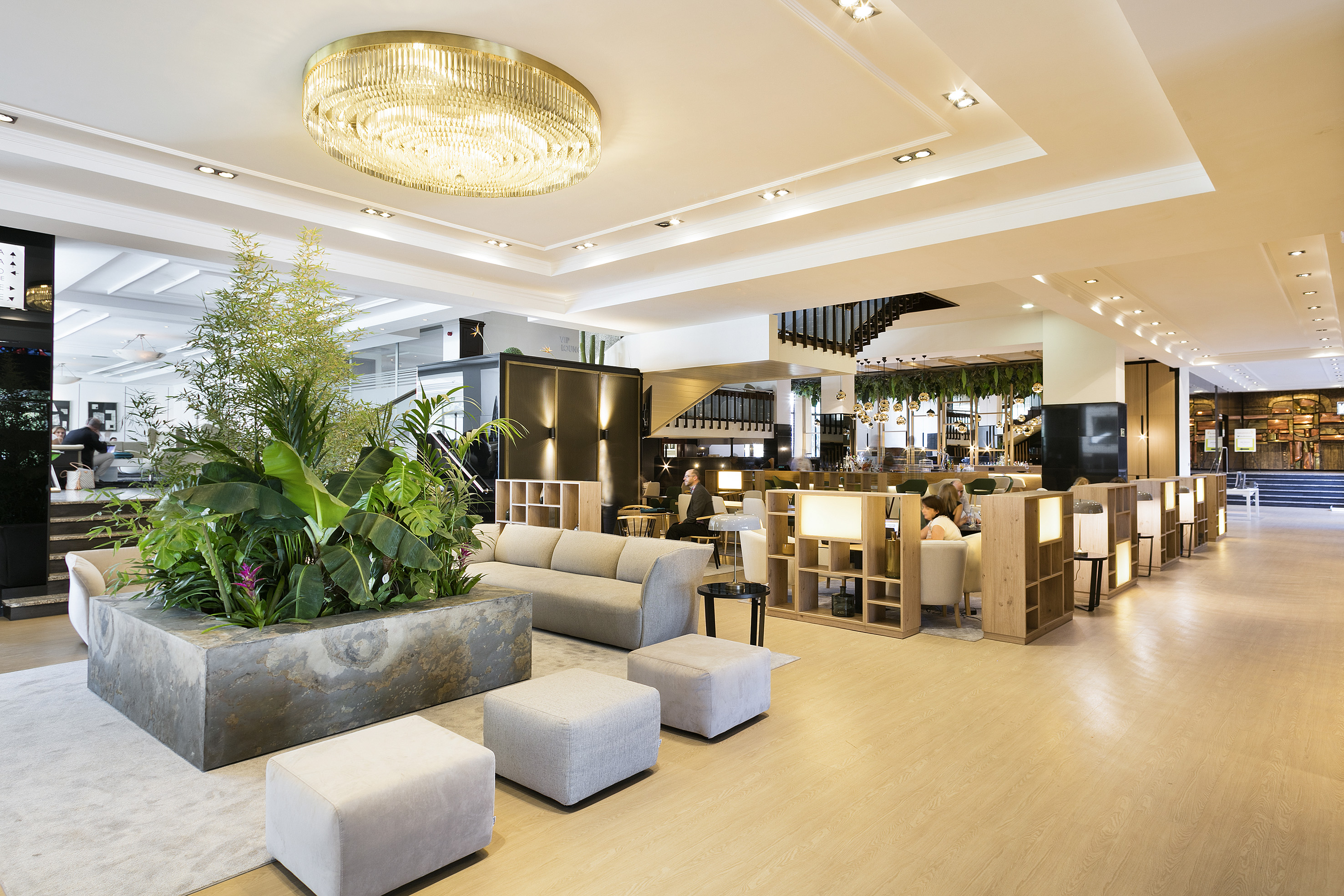Luxurious hotel lounge with lush plants, modern sofas, and gold chandelier.