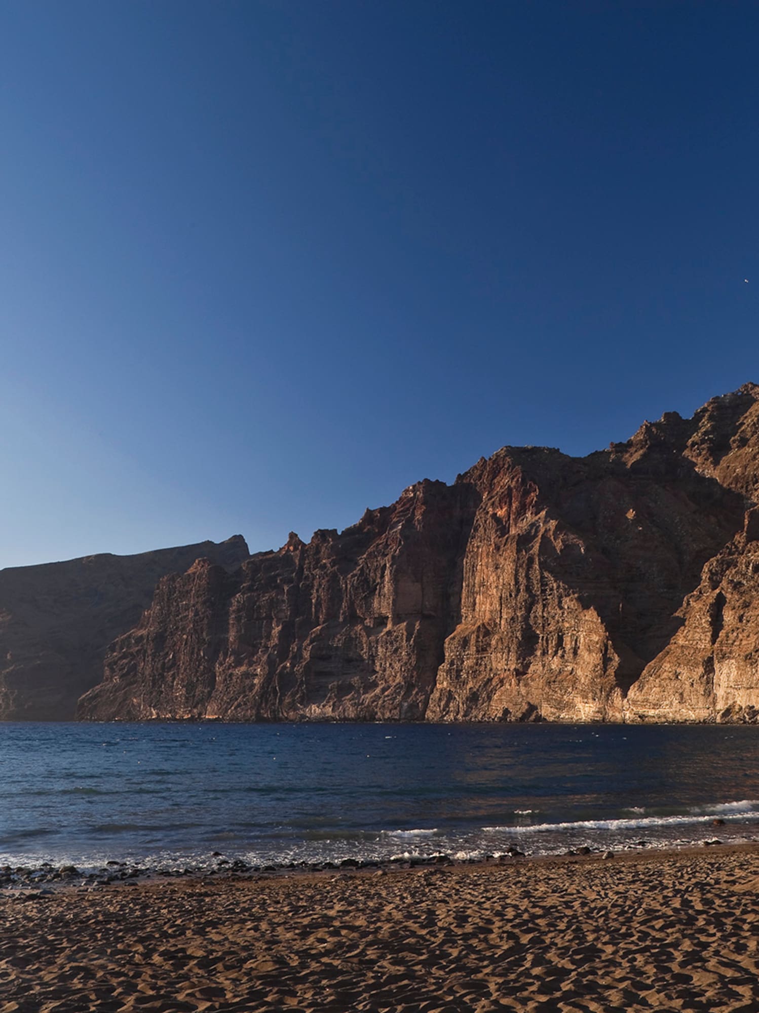 a beach with a body of water and mountains