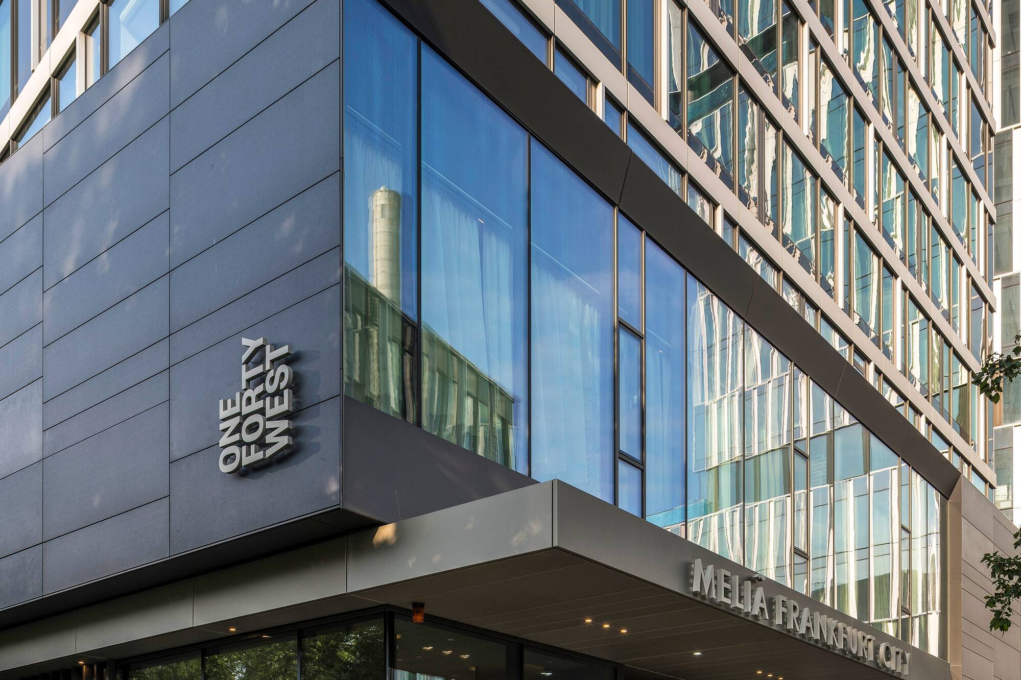Modern Meliá Frankfurt City hotel with glass facade and 'ONE FORTY WEST' sign.