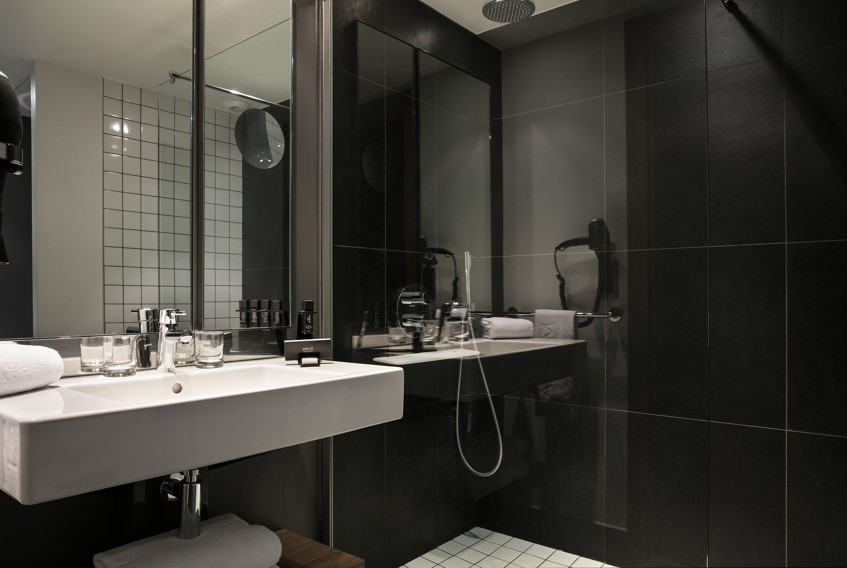 Contemporary bathroom with white floating sink, subway tiles, and black shower.
