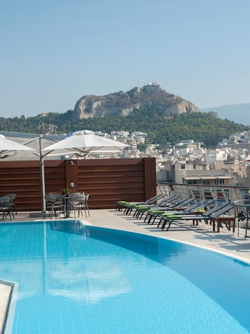 a pool with chairs and umbrellas on a rooftop