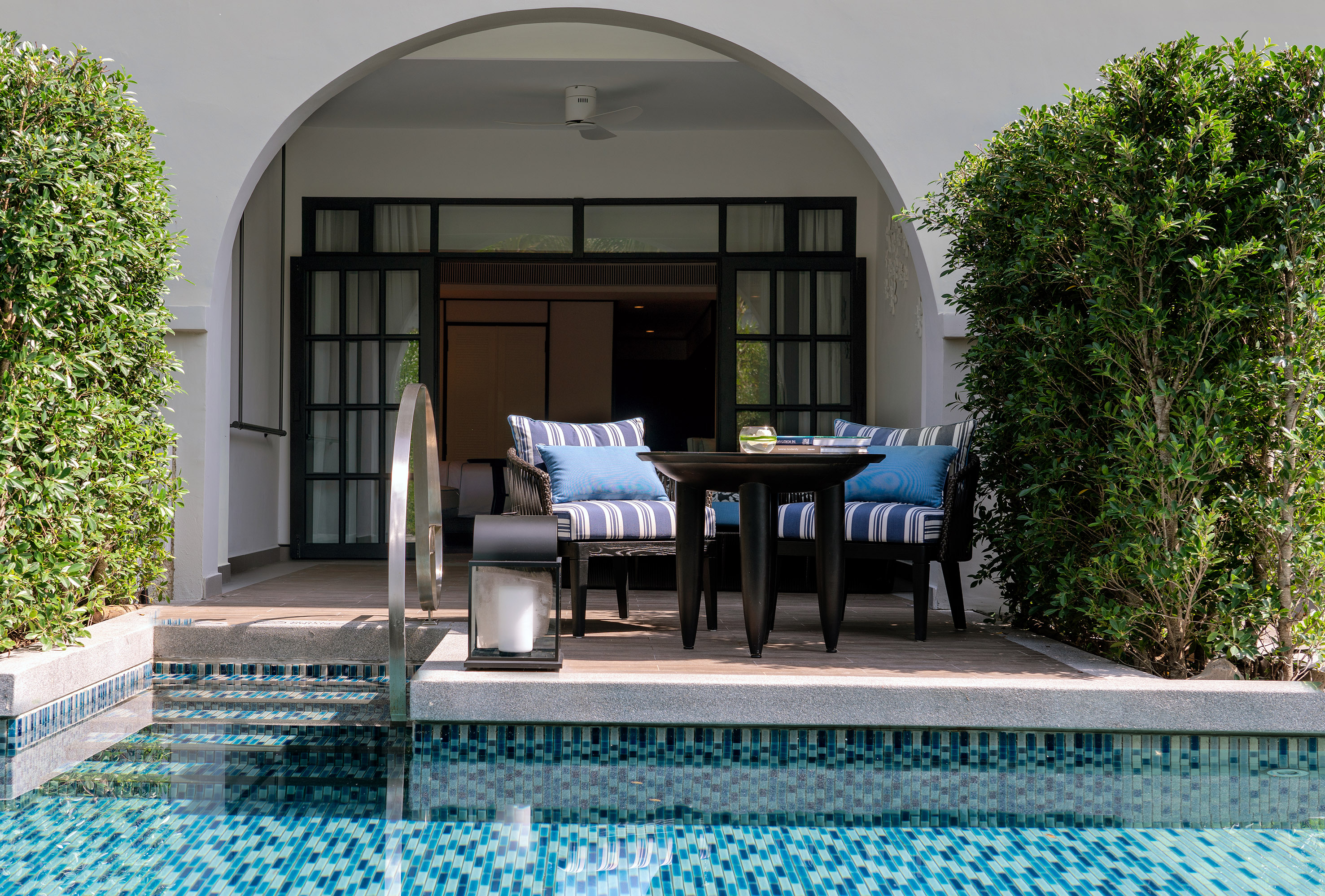 Shaded private pool patio with blue mosaic tiles, lounge chairs, and villa access.