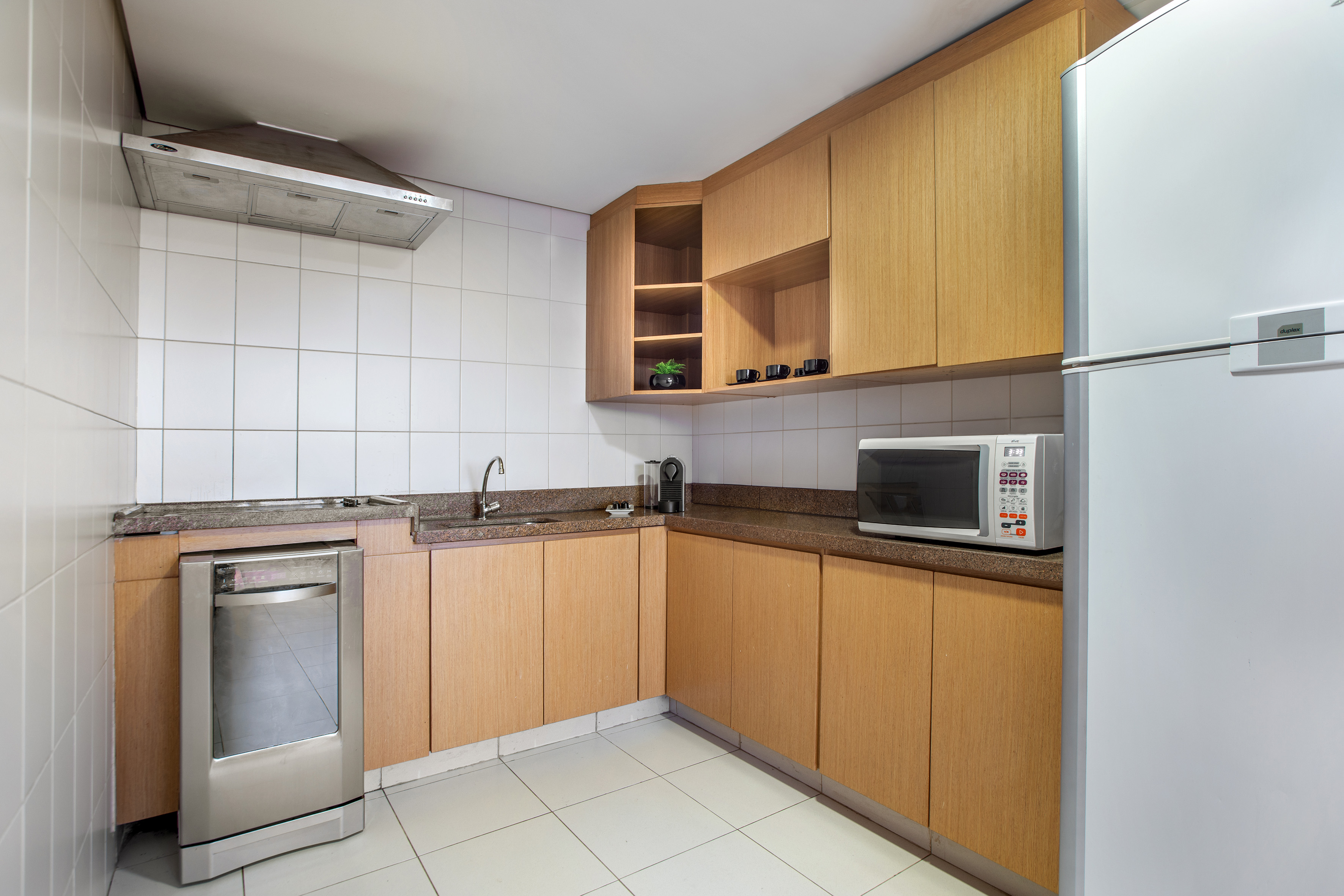 Modern kitchen with wood cabinets, granite counter, fridge, microwave, dishwasher.