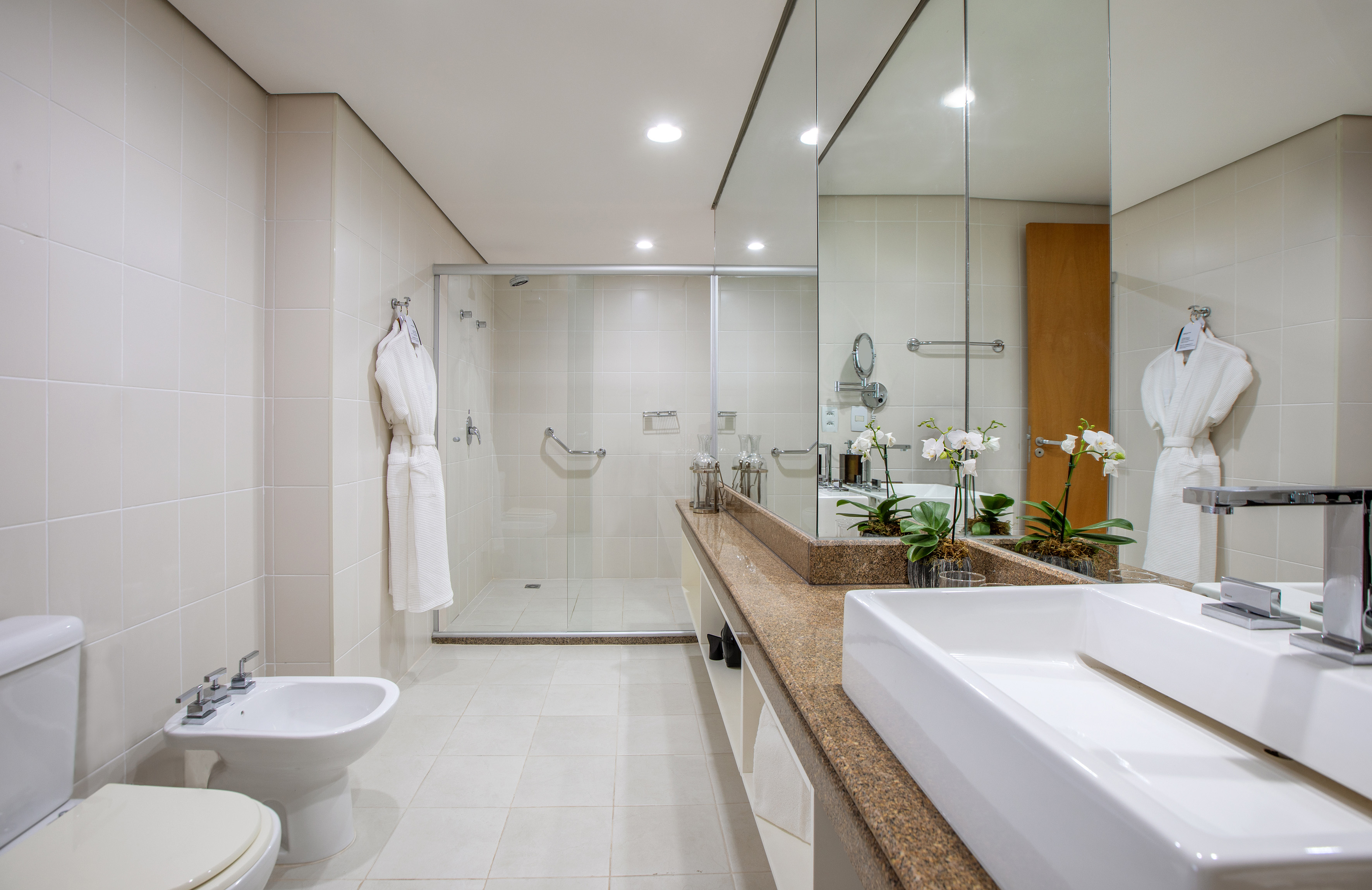 Bright modern bathroom with walk-in shower, granite vanity, and white sink.