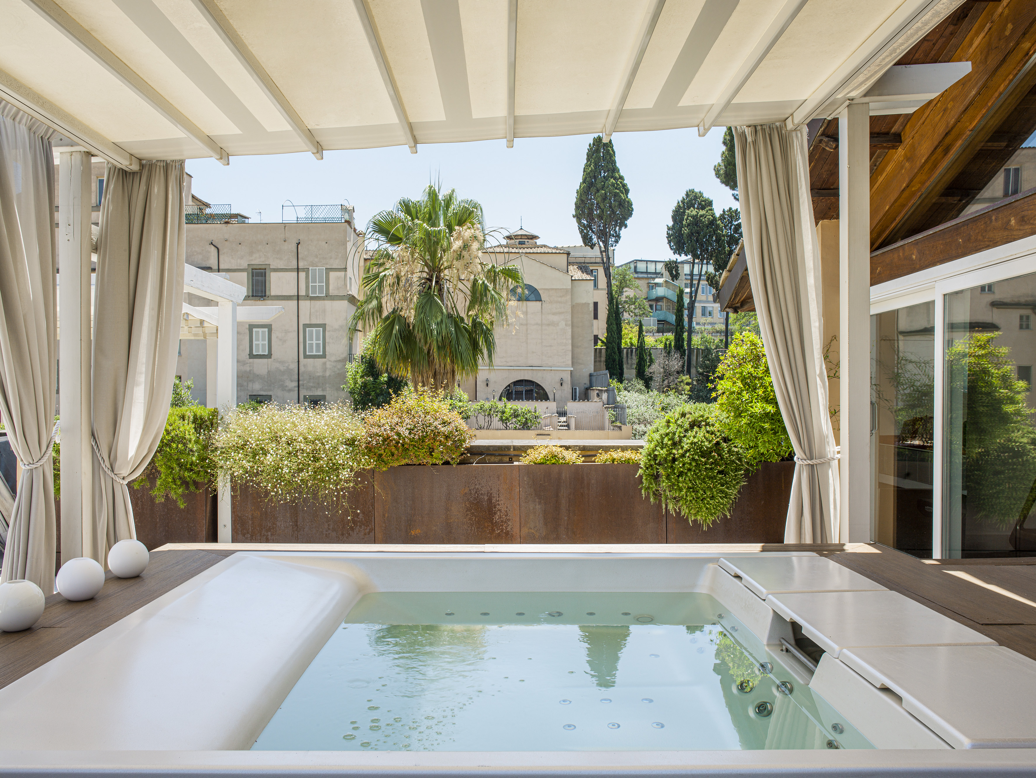 Outdoor hot tub on a luxury rooftop terrace with city views and pergola.