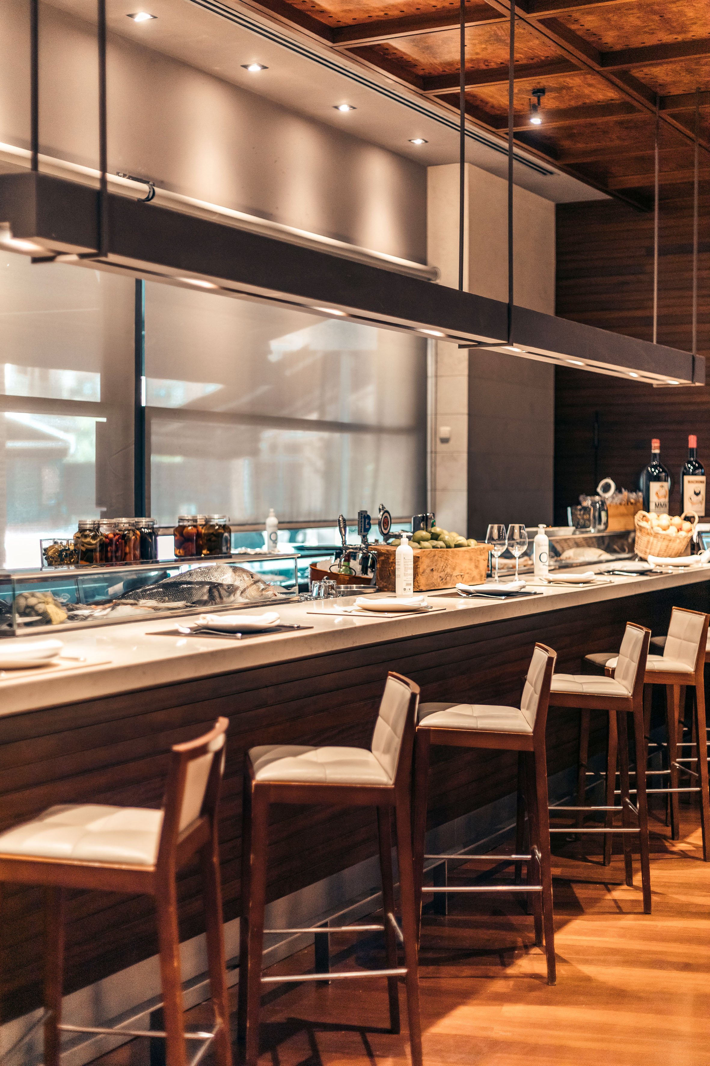 Modern seafood bar with fresh fish on ice and elegant counter stools.