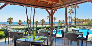 a restaurant with tables and chairs and a pool in the background