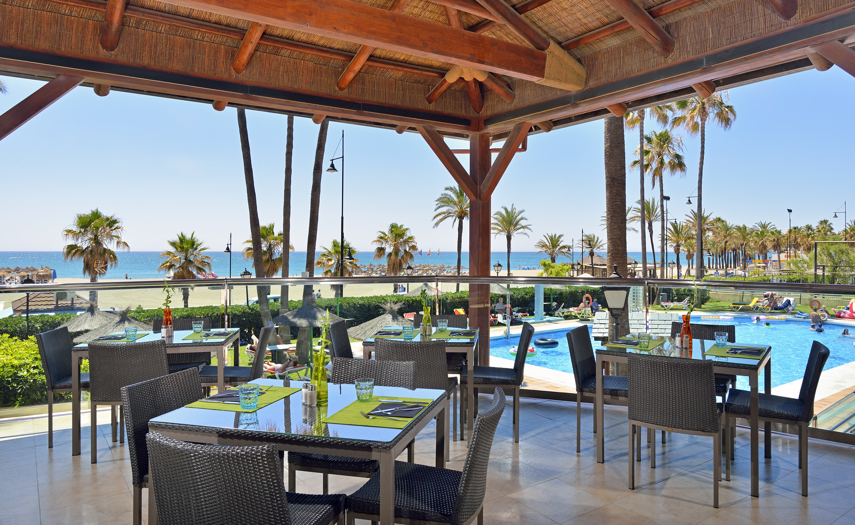 a restaurant with tables and chairs and a pool in the background