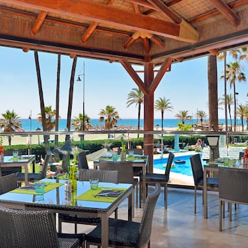 a restaurant with tables and chairs and a pool in the background