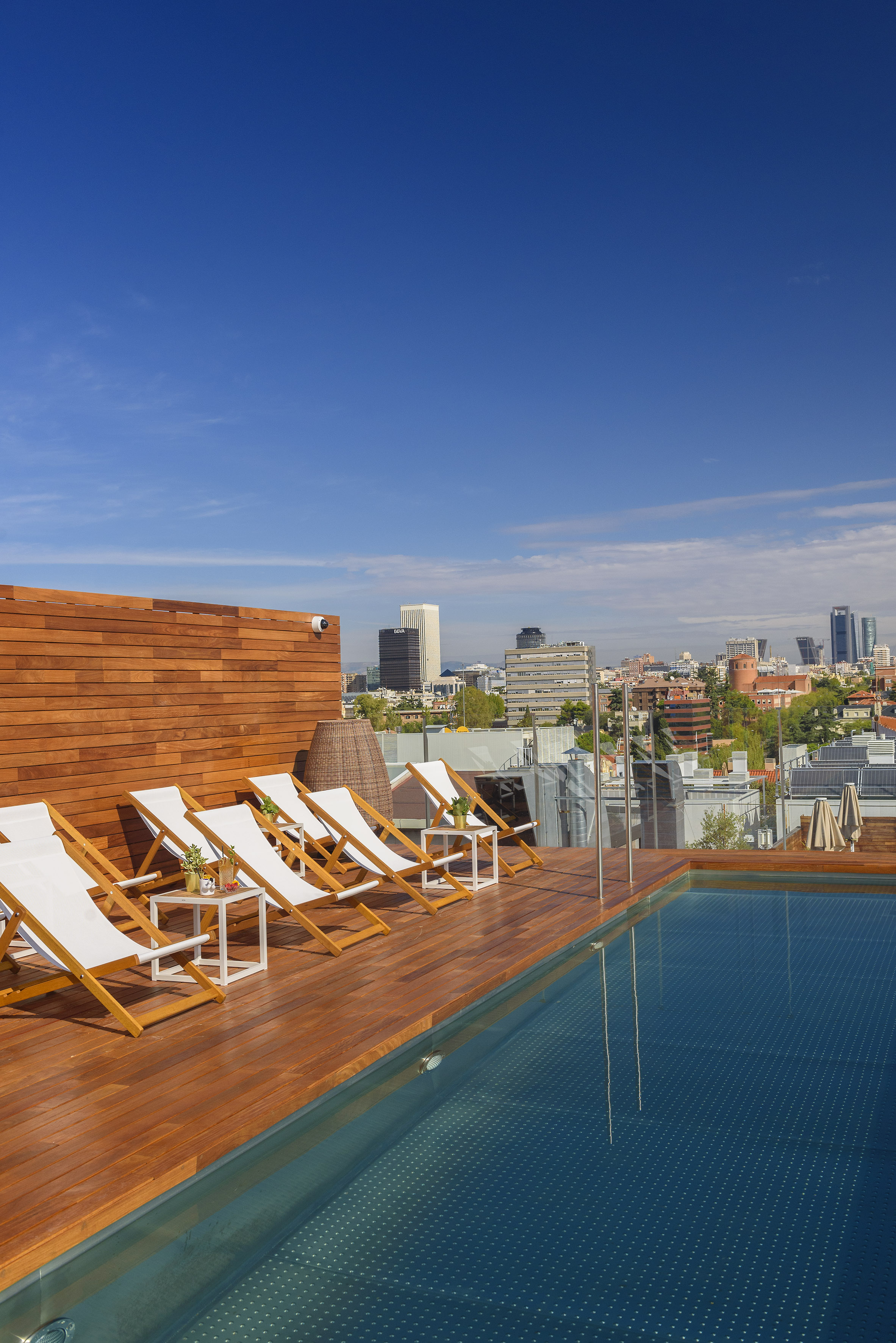 a pool with chairs on a rooftop