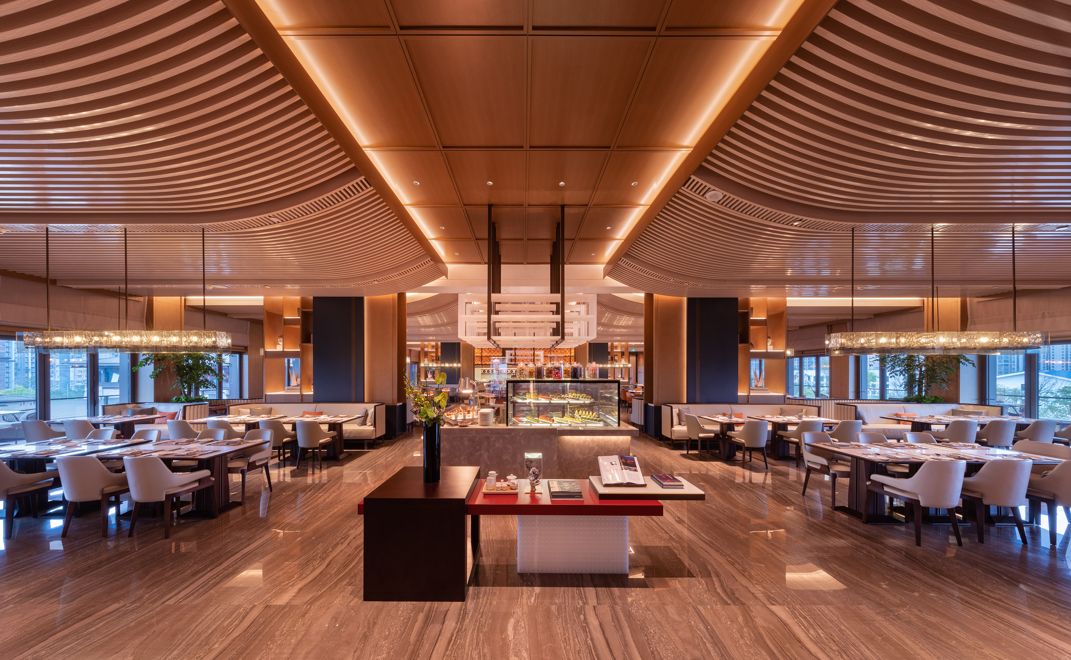 Elegant modern hotel restaurant with wooden ceilings, marble floors, and buffet.