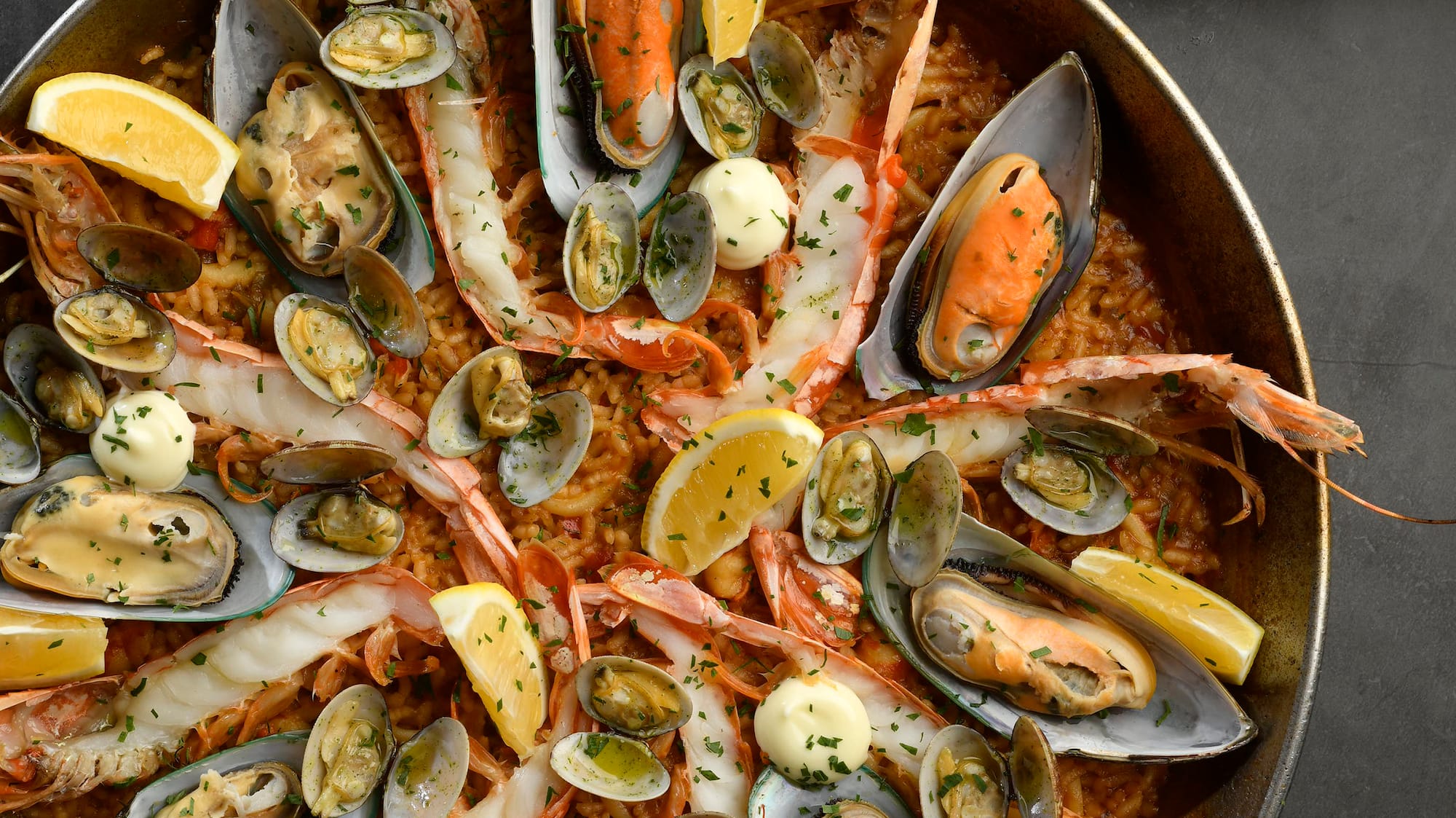 a pan of seafood with lemons and sauce