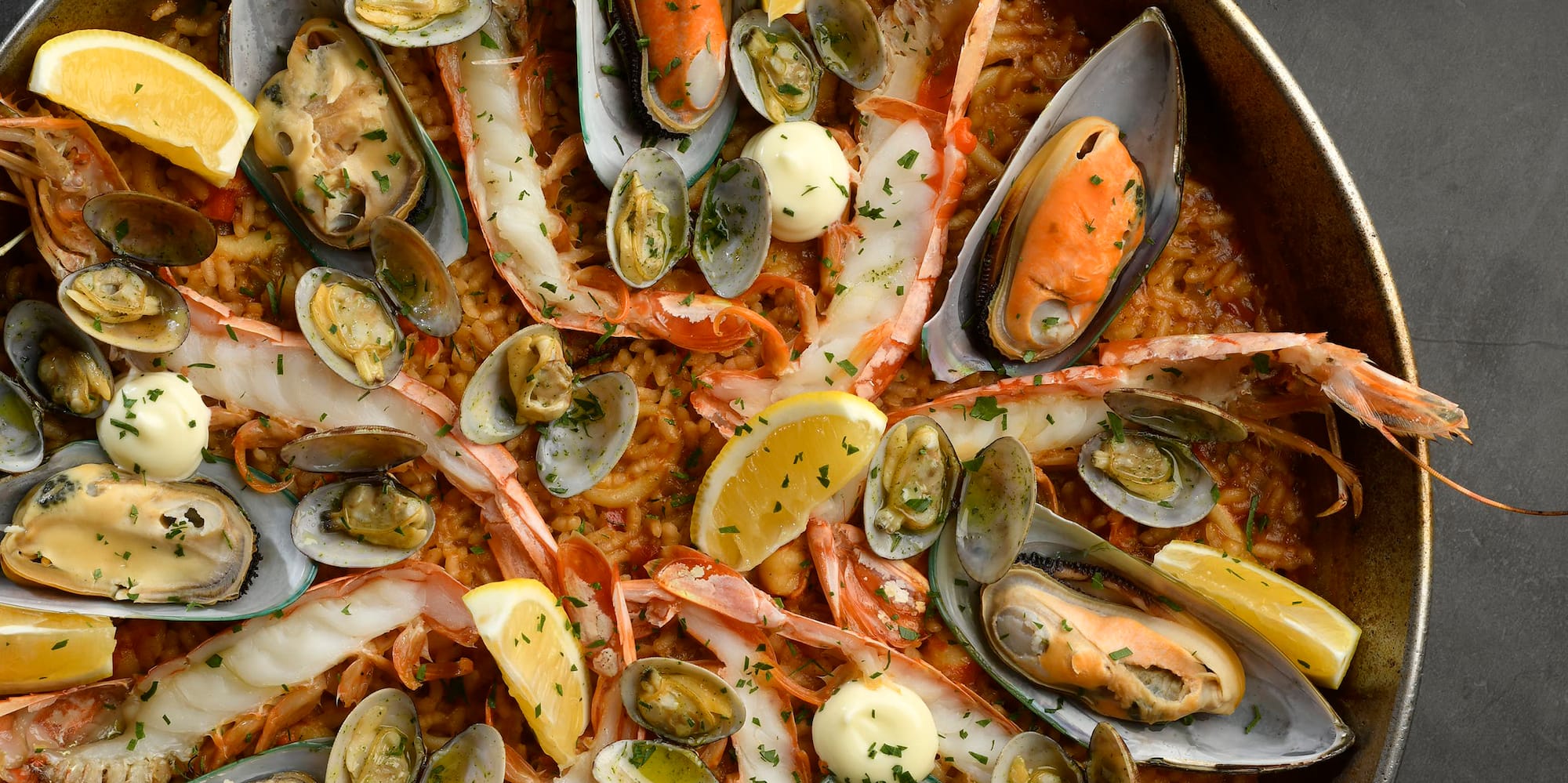 a pan of seafood with lemons and sauce