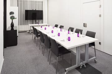 a long conference room with white tables and purple glasses