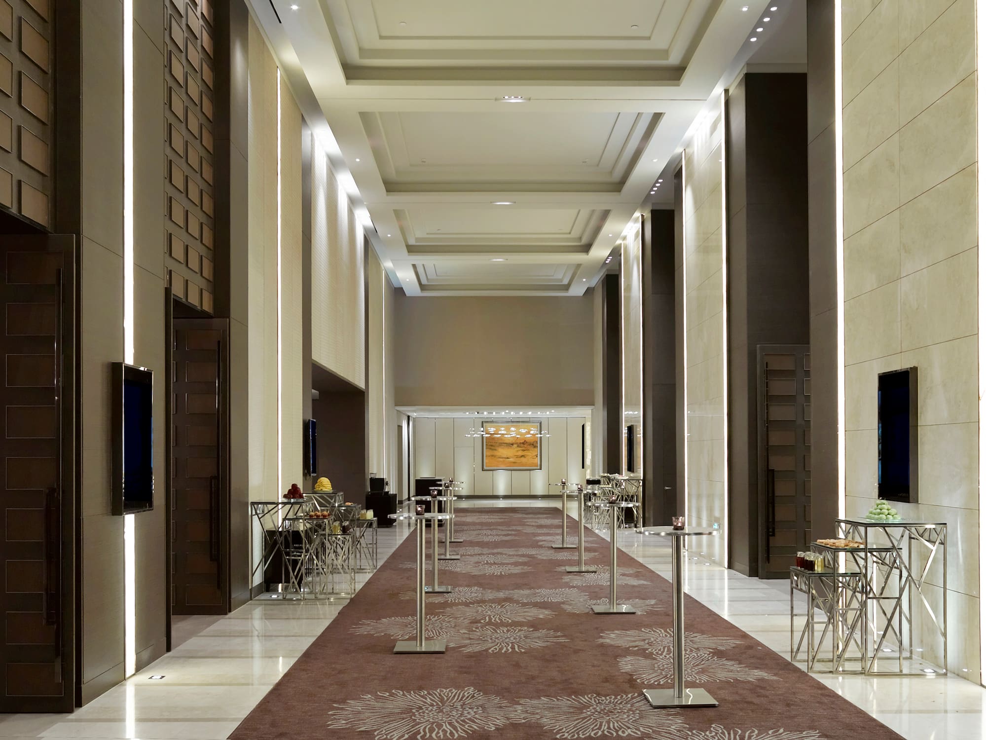 a long hallway with a carpeted area and a television