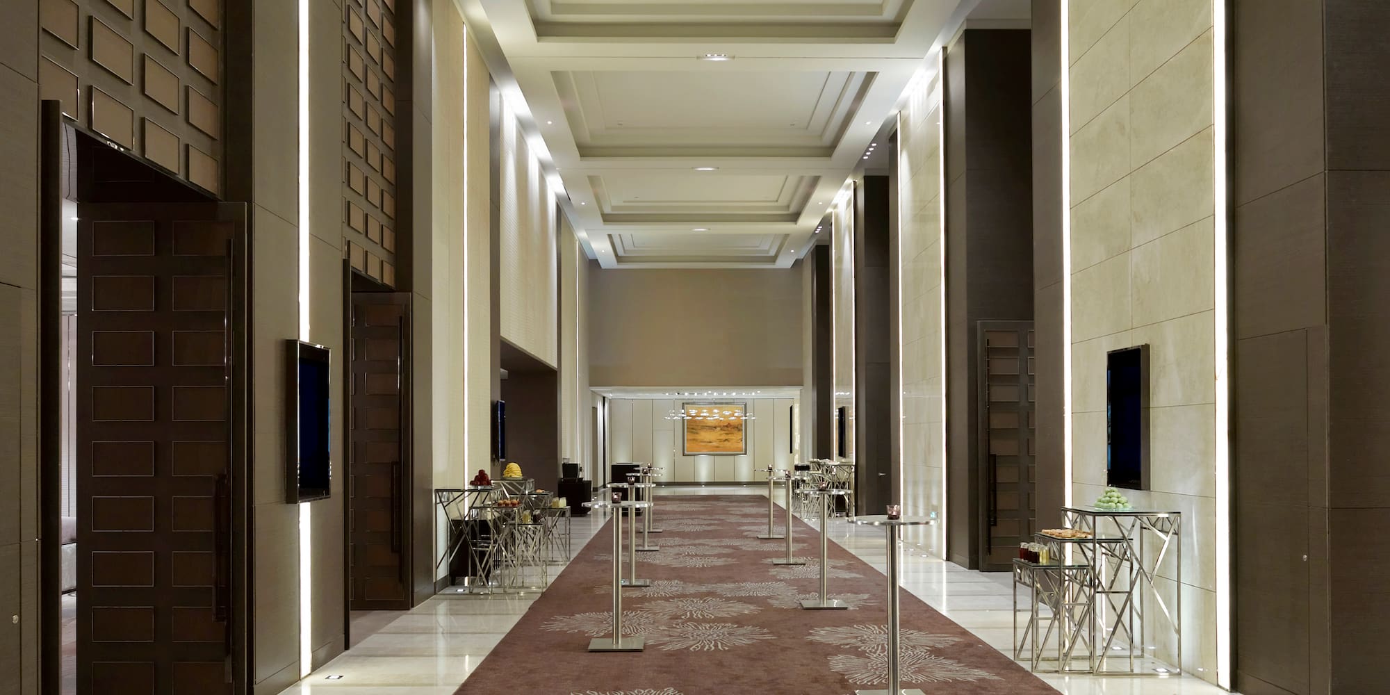 a long hallway with a carpeted area and a television