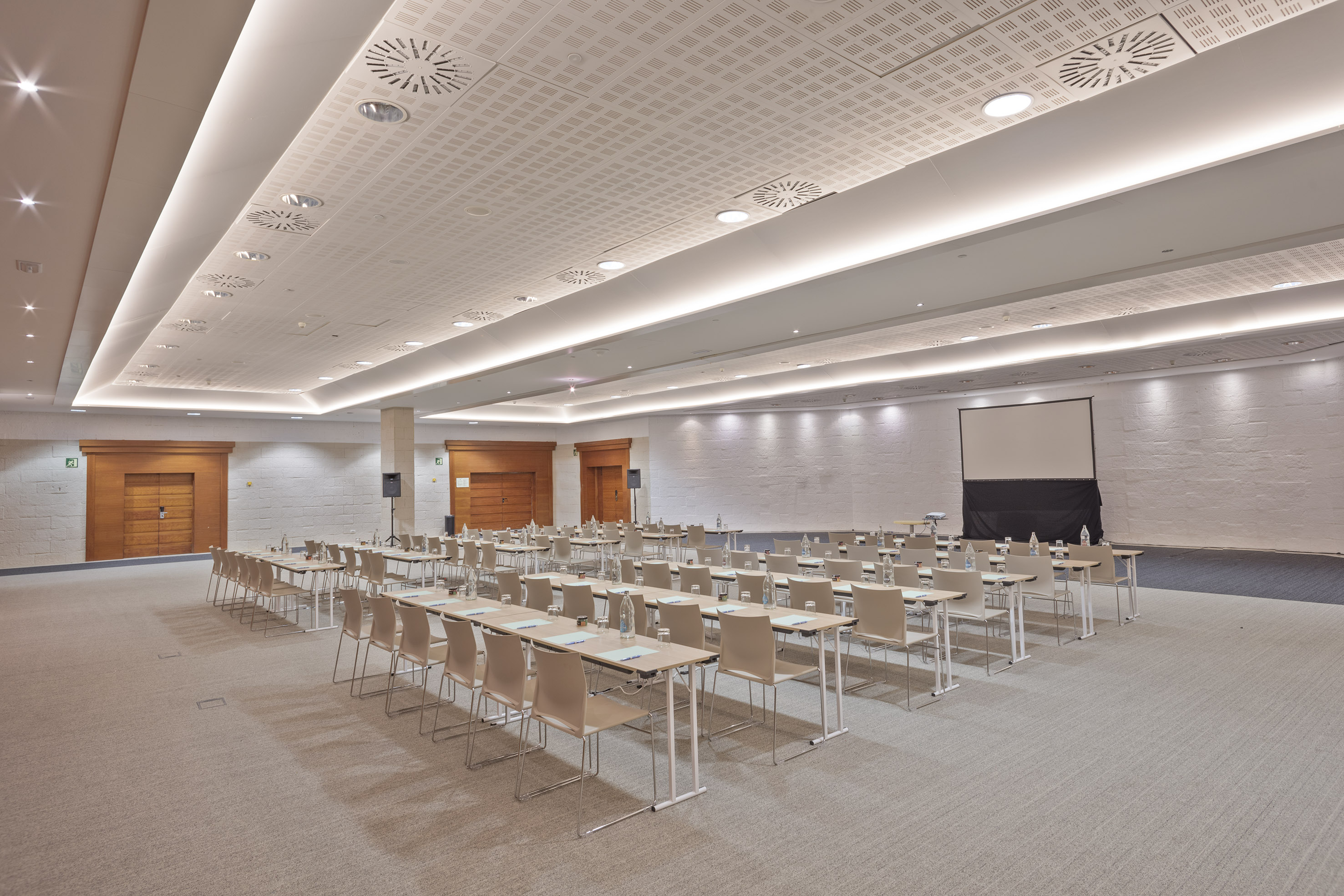 Empty modern conference room with classroom setup, projection screen, and bright lighting.