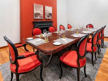 a table with red chairs and a fireplace