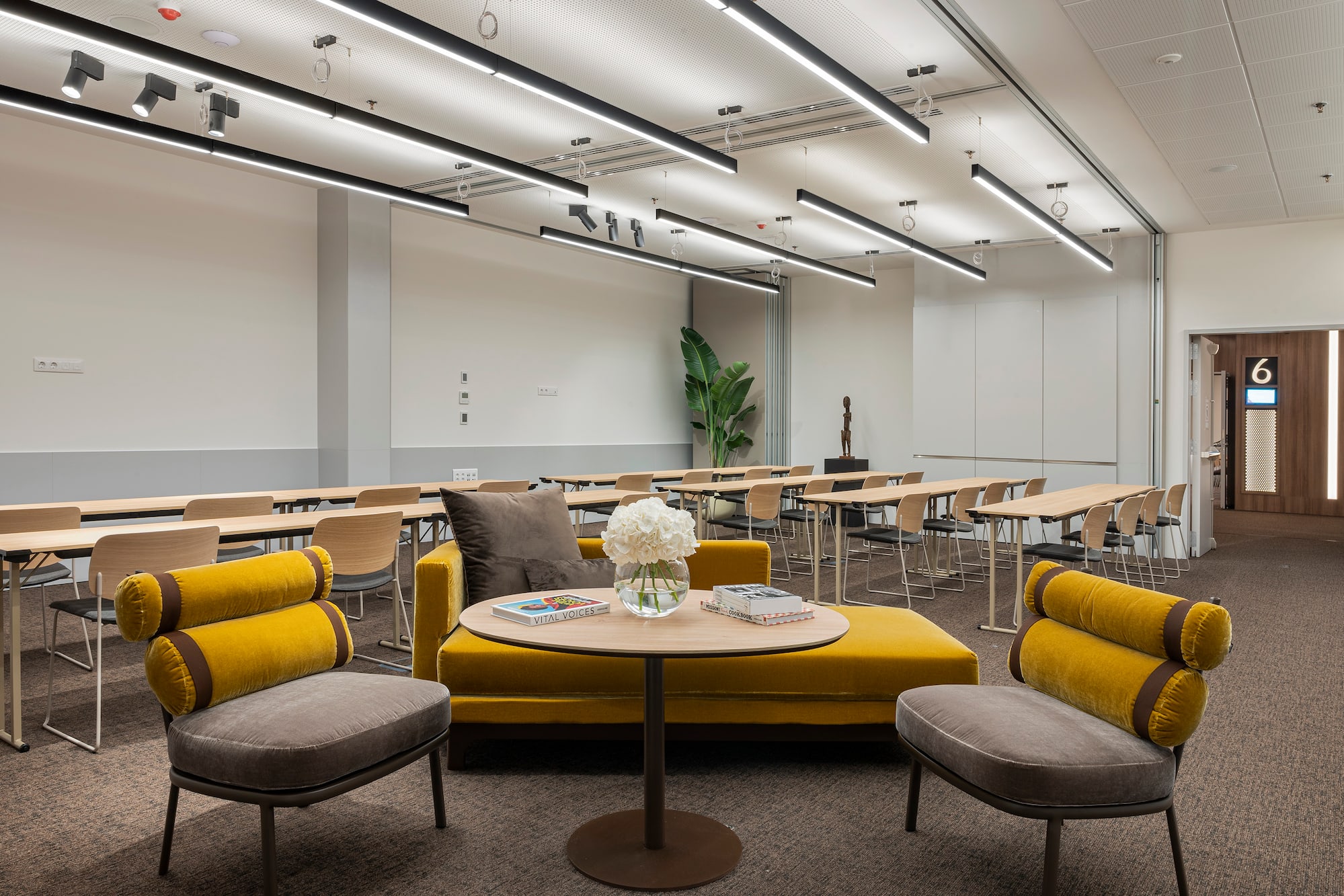 Flexible meeting room with yellow lounge, training tables, and modern lighting.