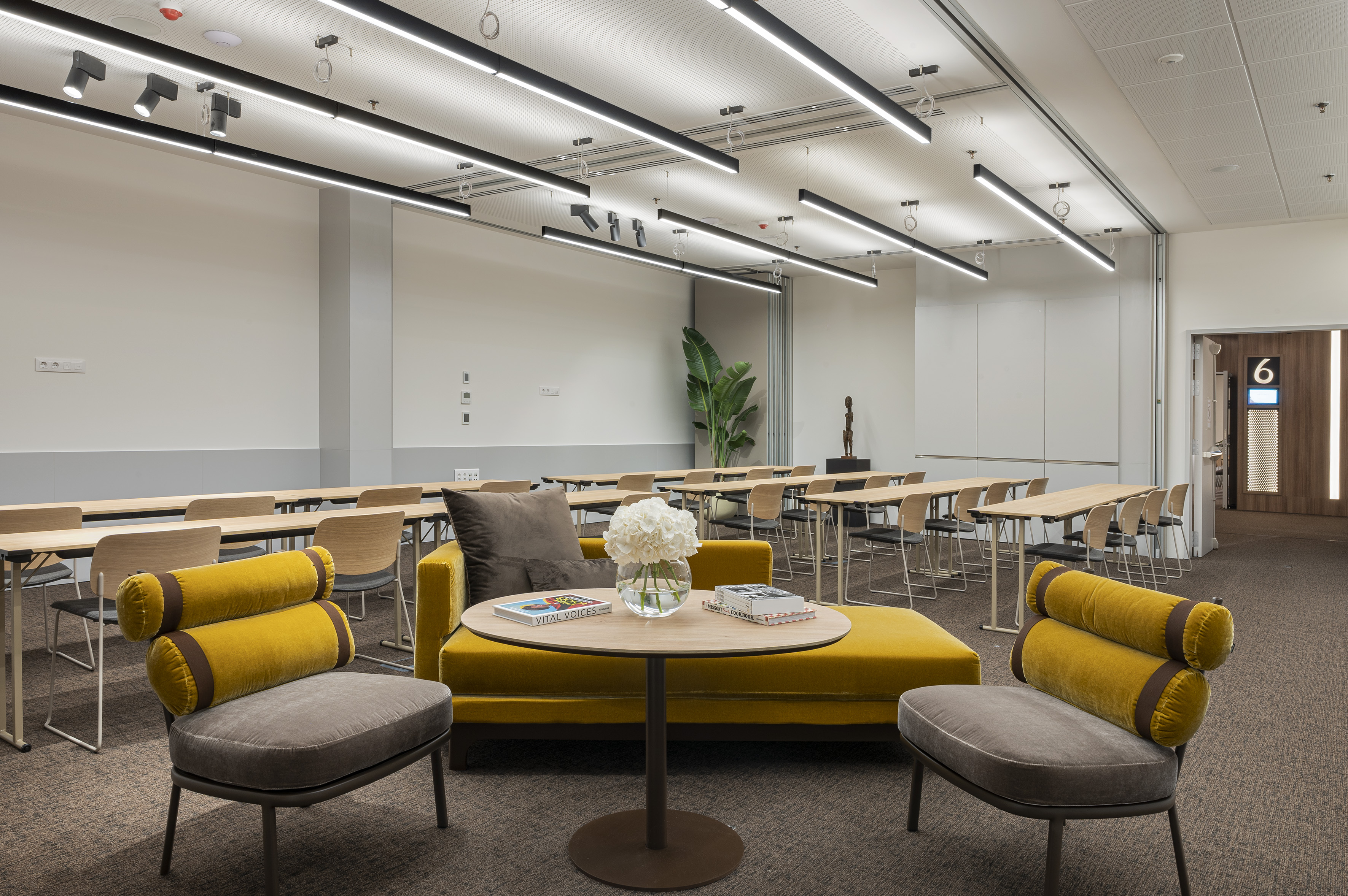 Flexible meeting room with yellow lounge, training tables, and modern lighting.