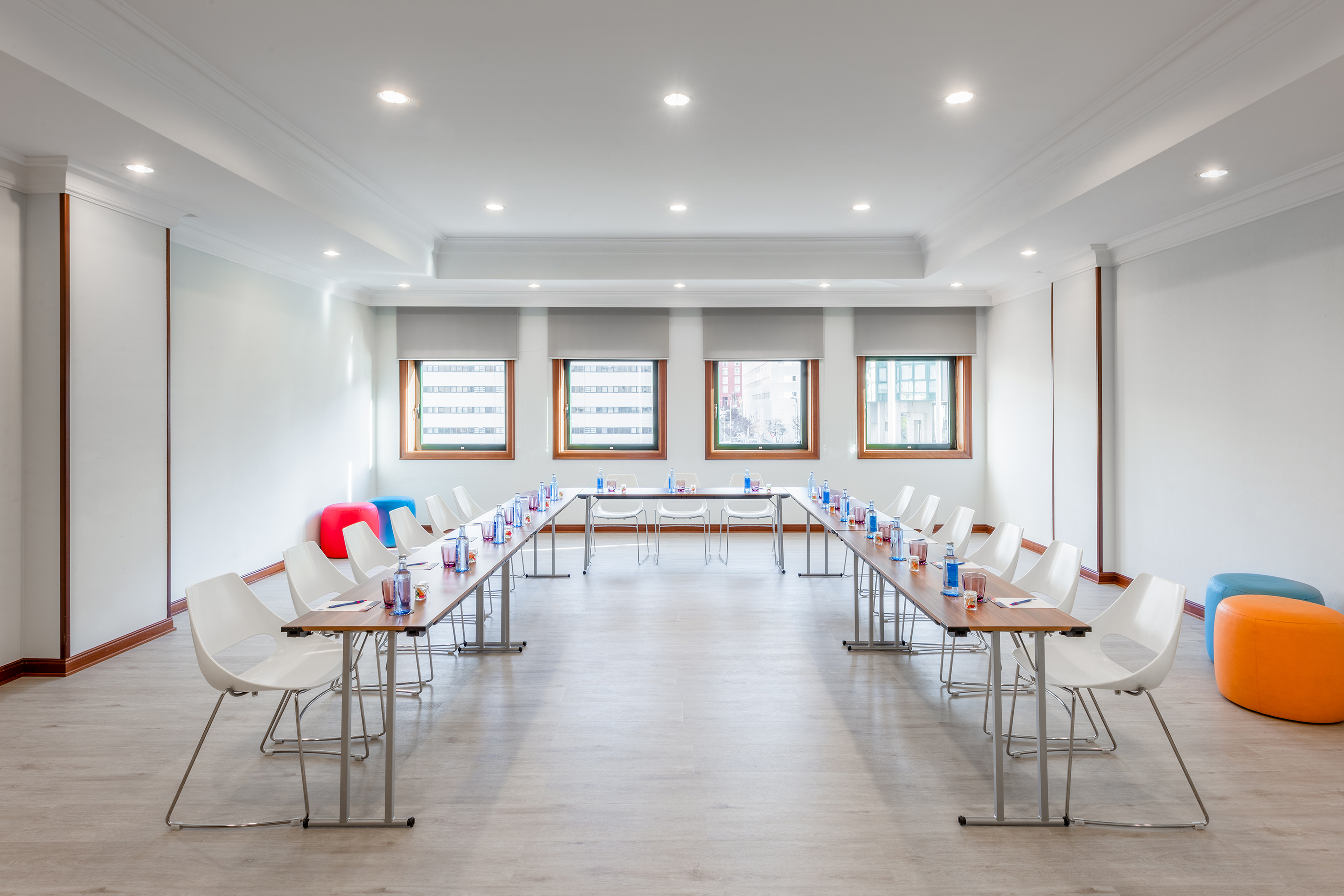 Modern U-shaped meeting room with white chairs and colorful seating.