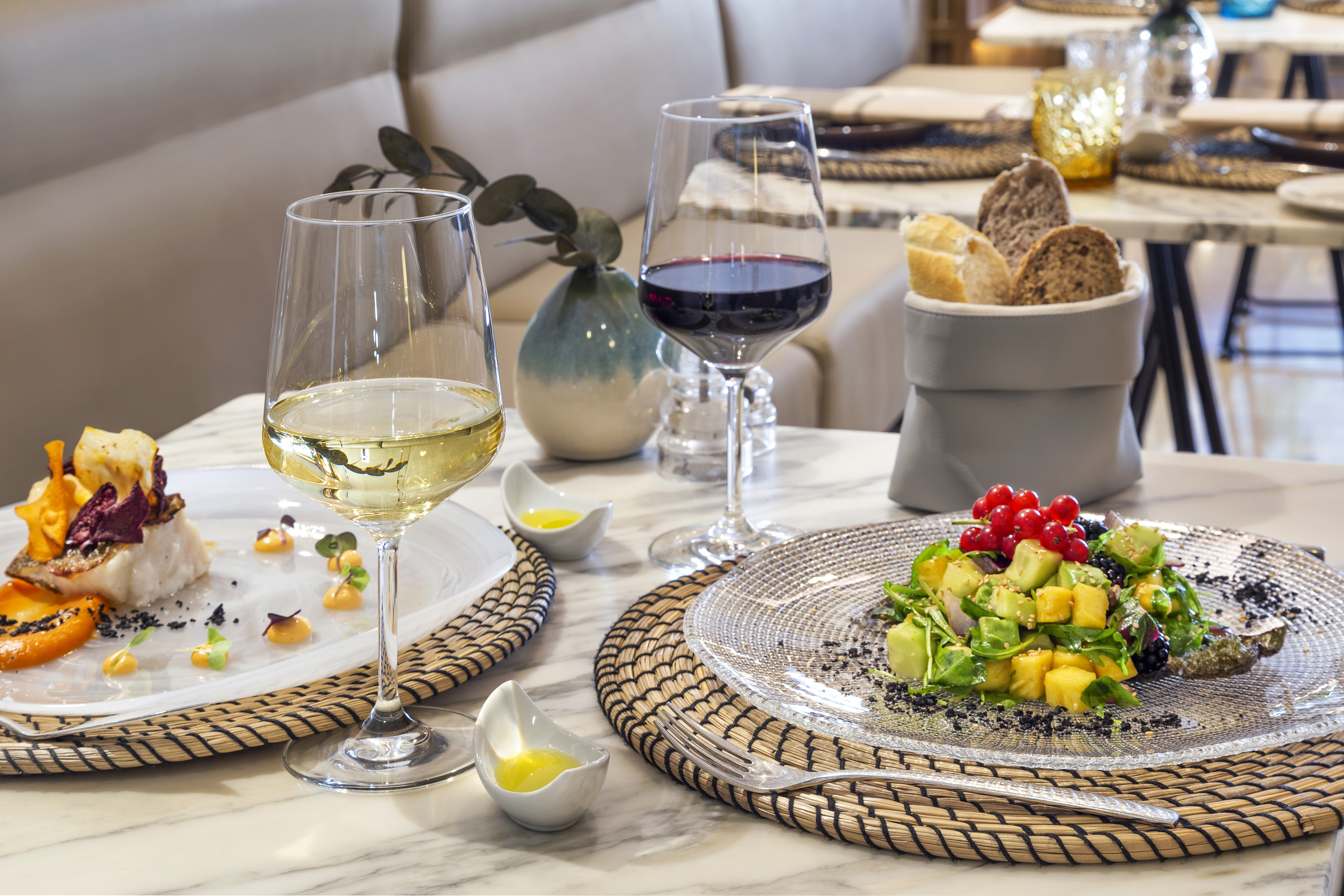 Gourmet fish and avocado salad with white and red wine at a restaurant.