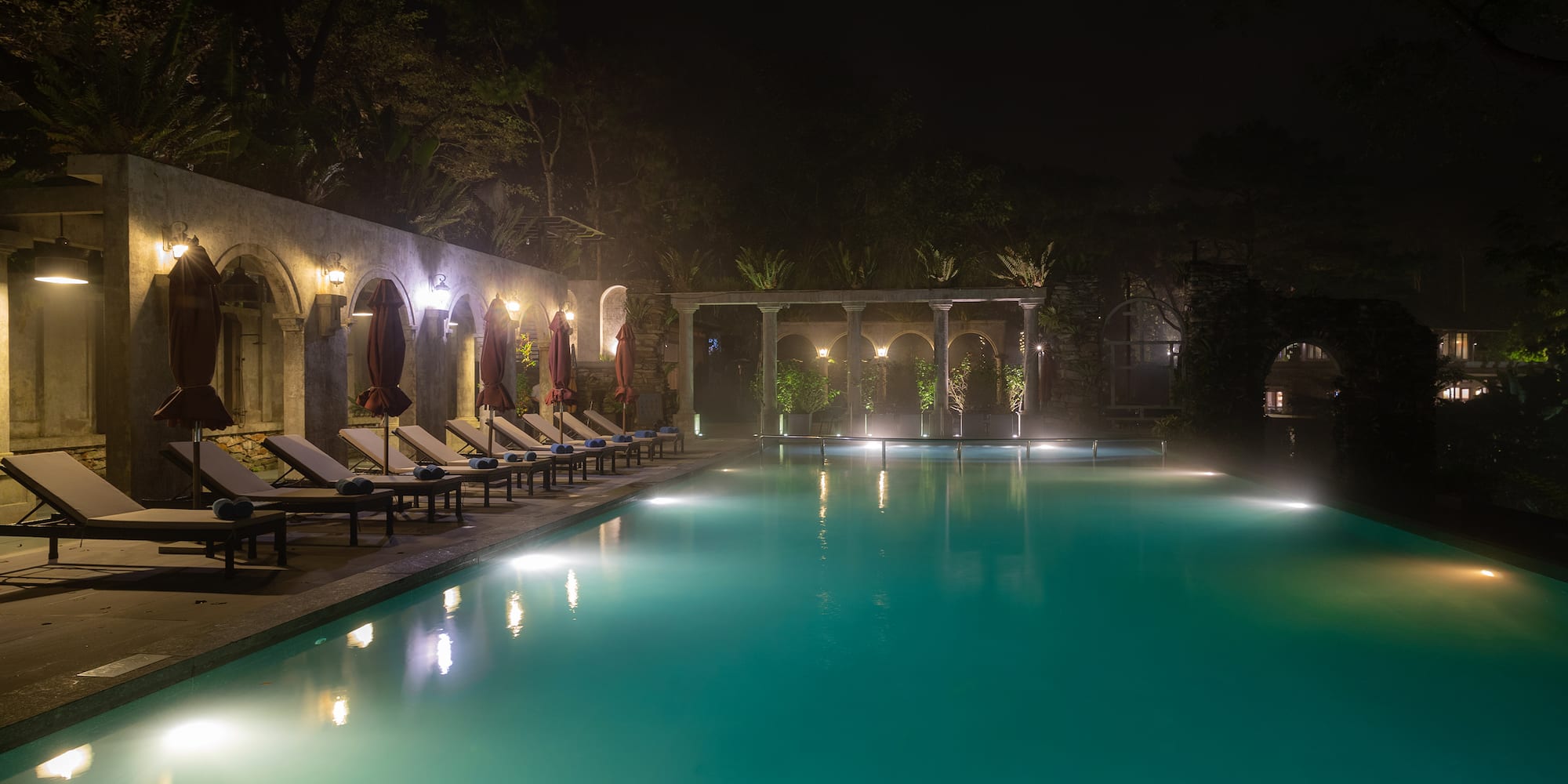 a pool with chairs and a stone wall
