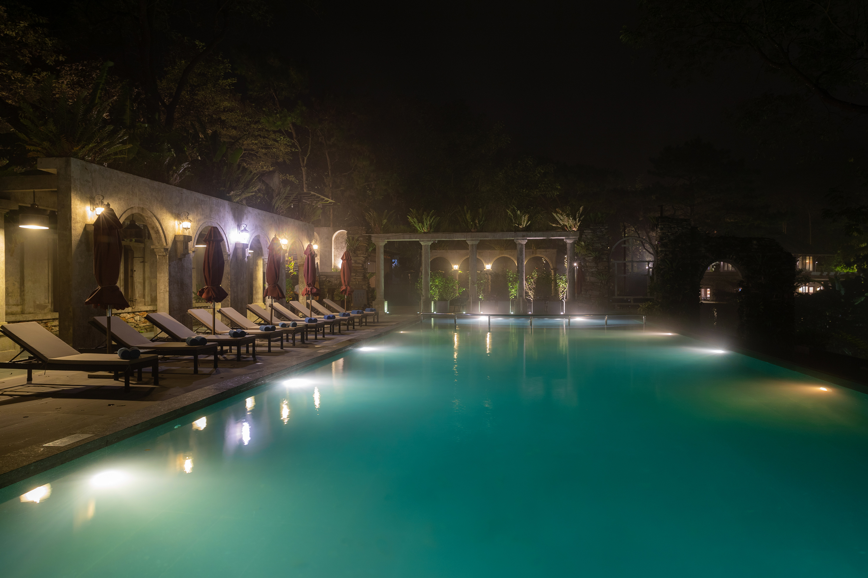 a pool with chairs and a stone wall