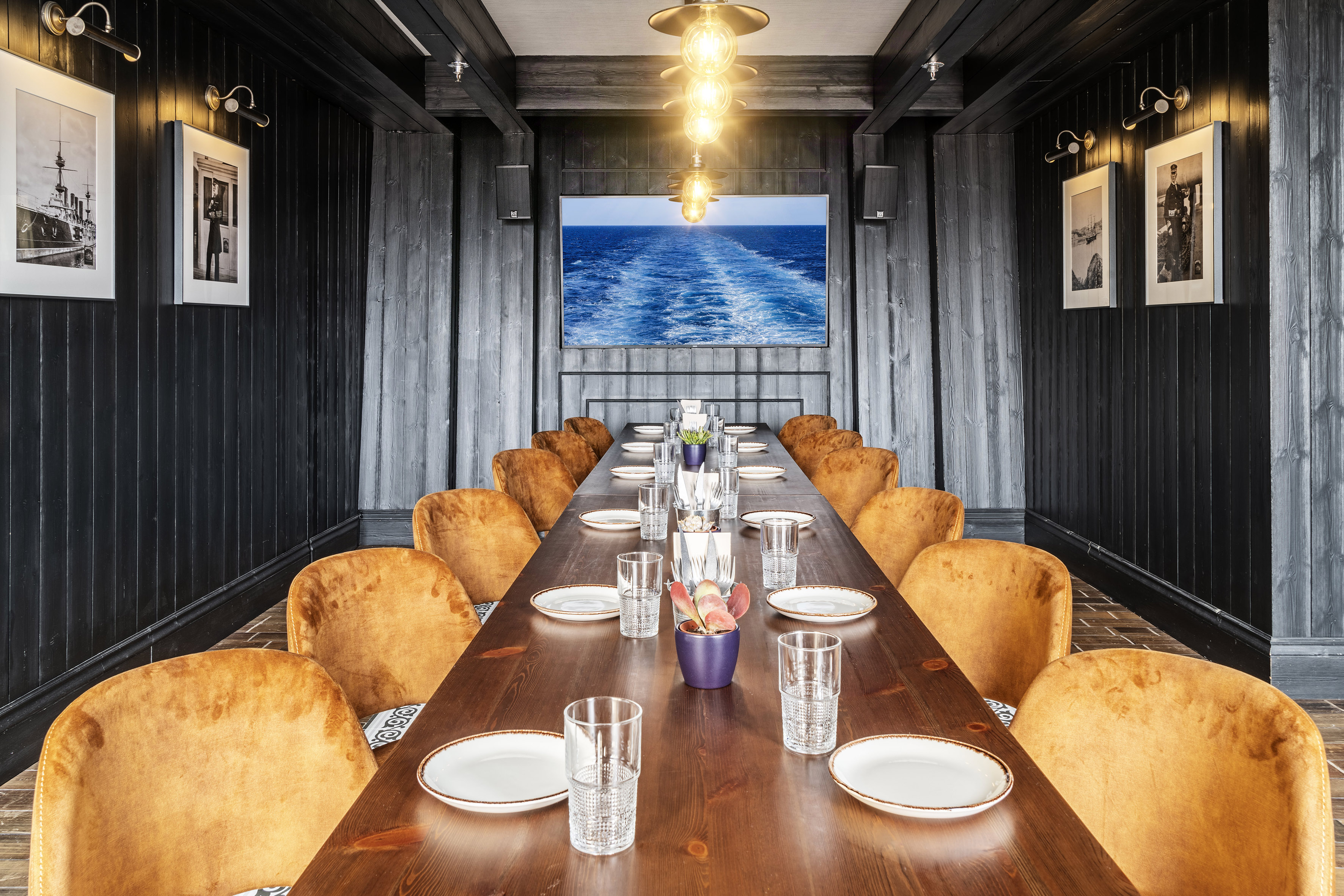 Dark wood private dining room with long table, golden chairs, nautical decor.