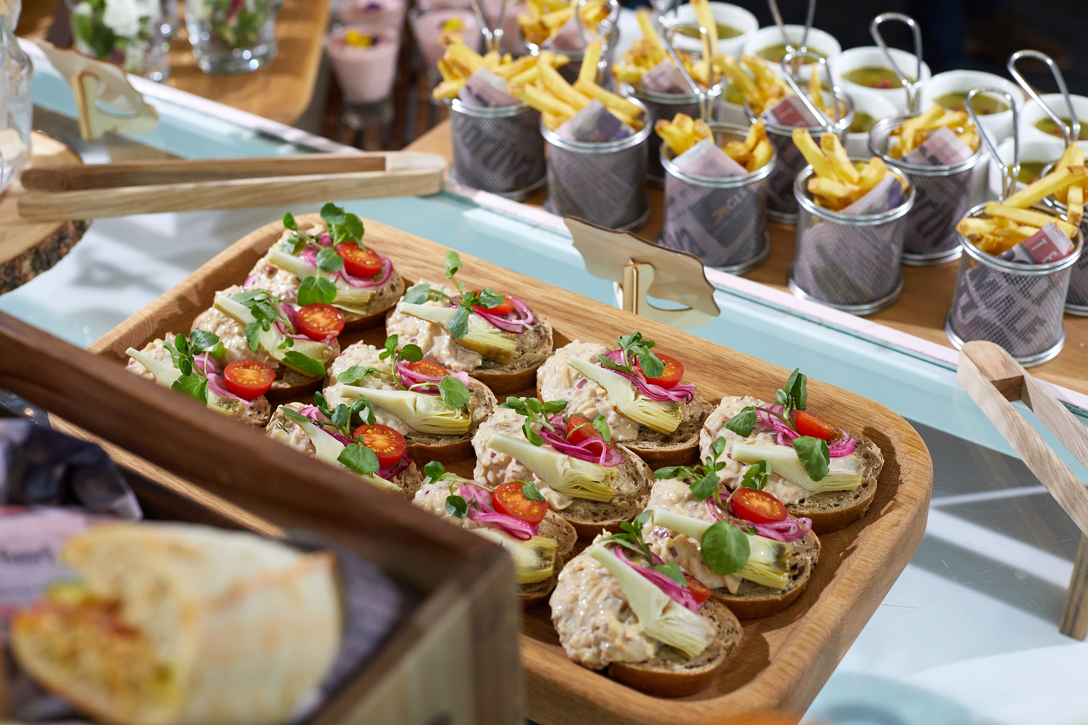 Gourmet canapés with artichoke, tomato, red onion on wooden tray, buffet food.