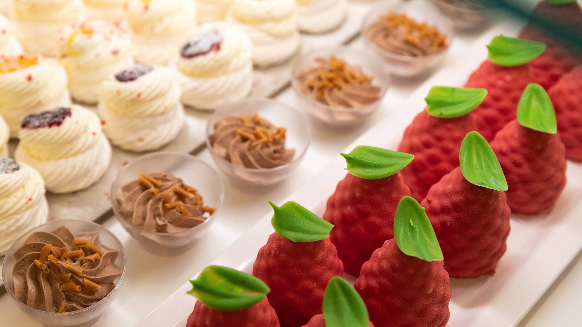 a tray of desserts with red strawberries and green leaves