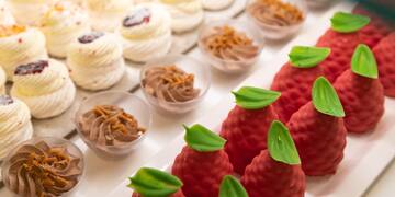 a tray of desserts with red strawberries and green leaves
