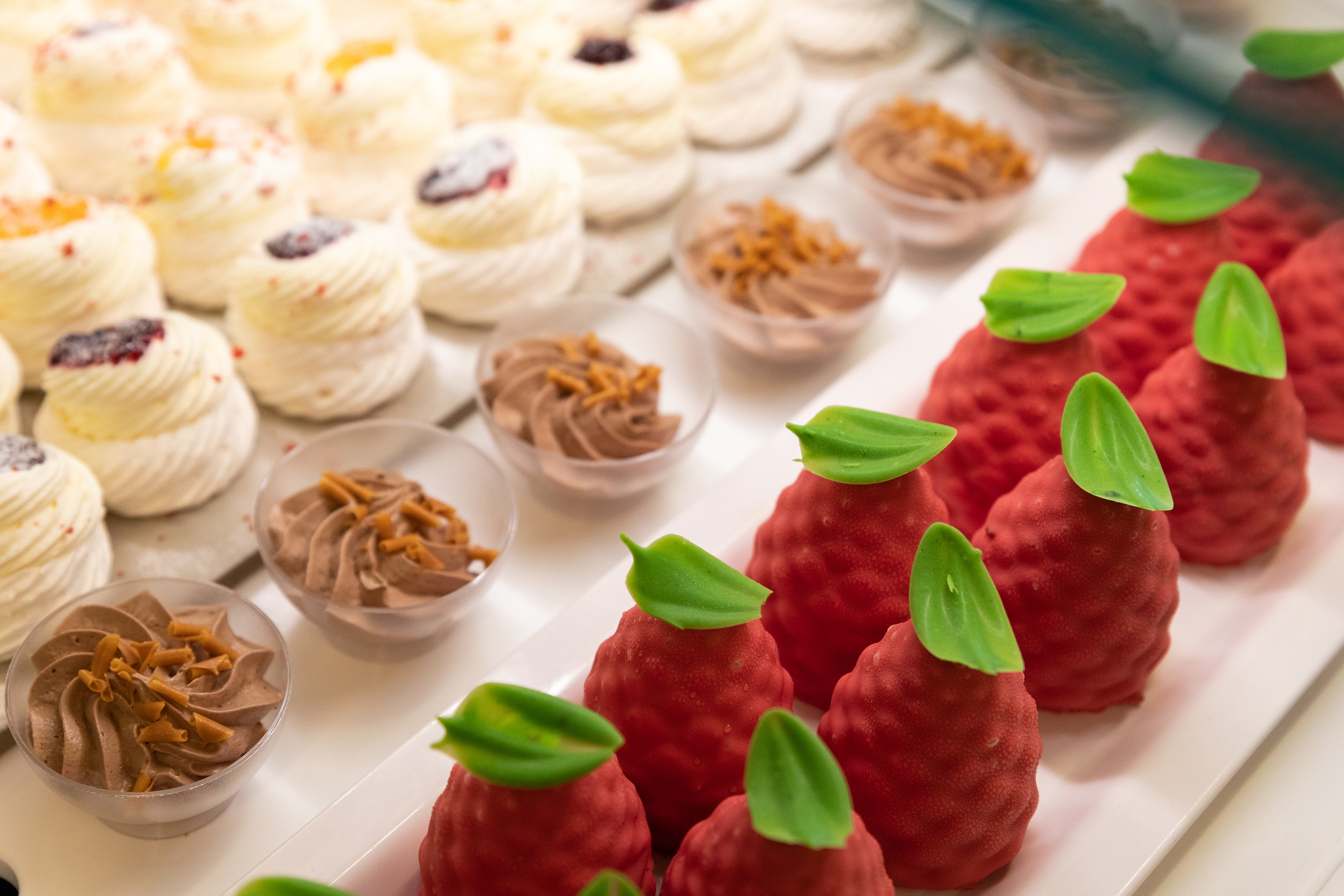 a tray of desserts with red strawberries and green leaves