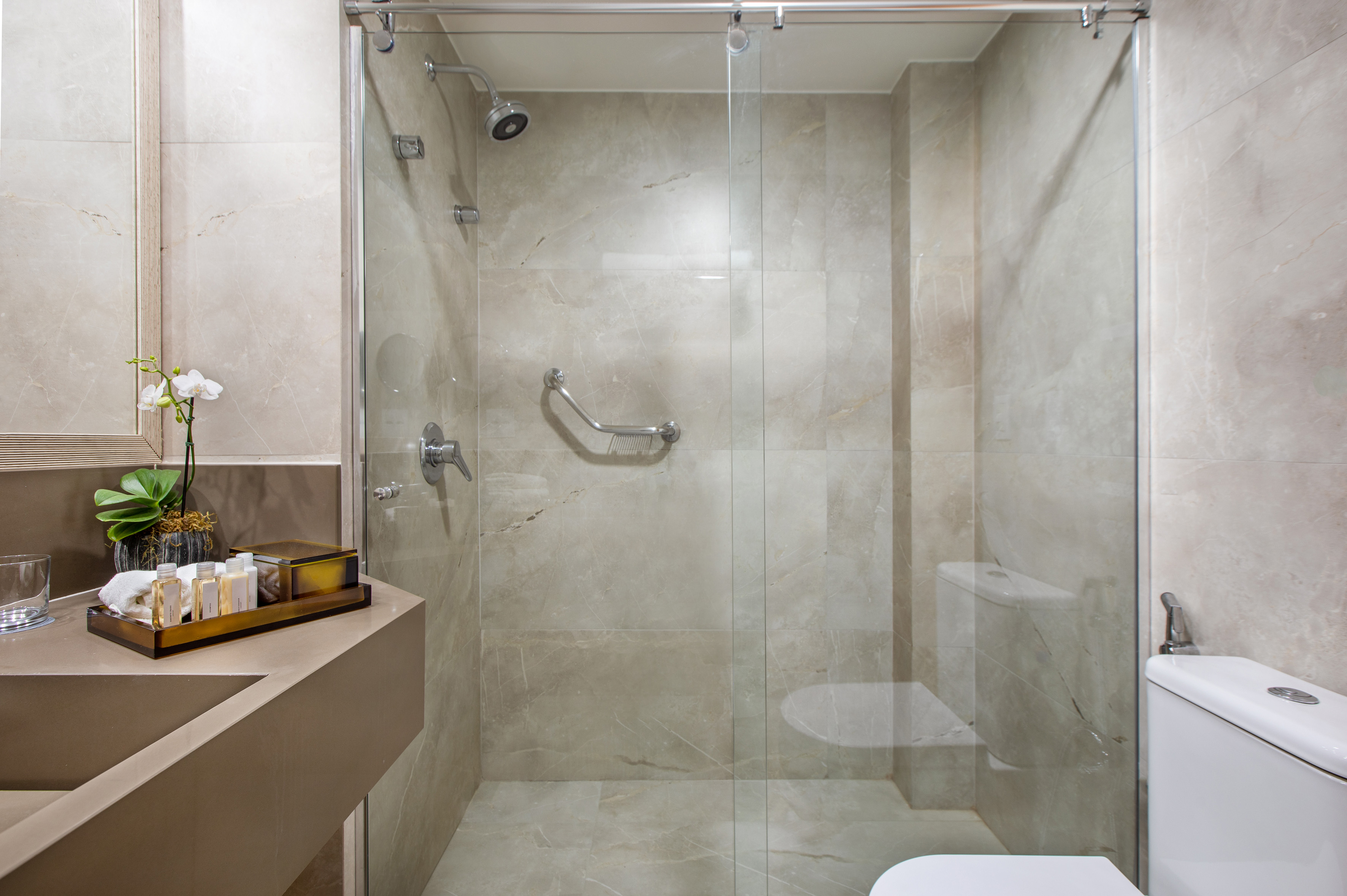 Modern bathroom with walk-in shower, grab bar, vanity, and toilet.
