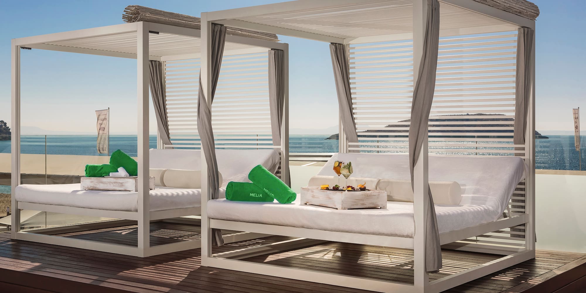 a group of white beds with green pillows on a deck