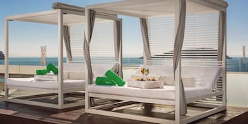 a group of white beds with green pillows on a deck