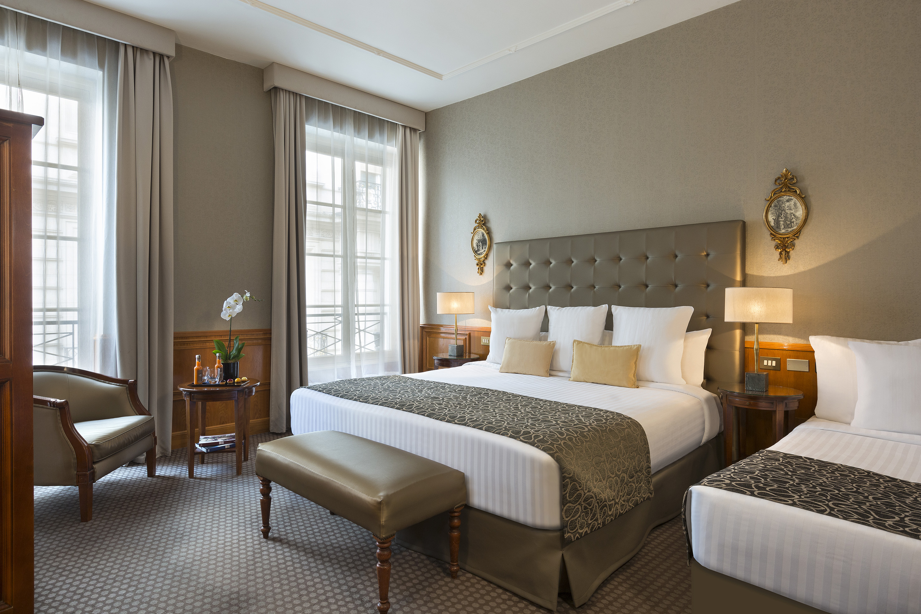 Elegant hotel room with a king bed, single bed, and classic decor.