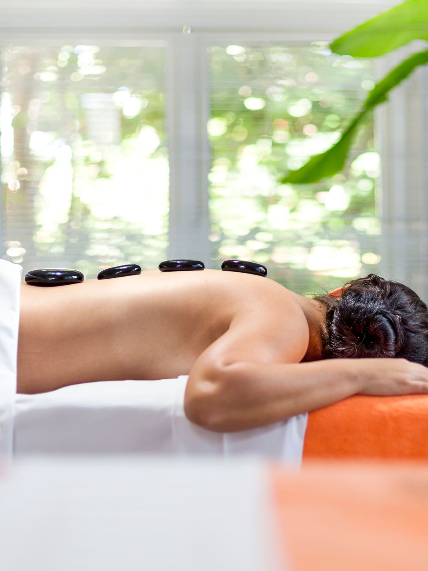 a woman lying on a bed with a stone on her back