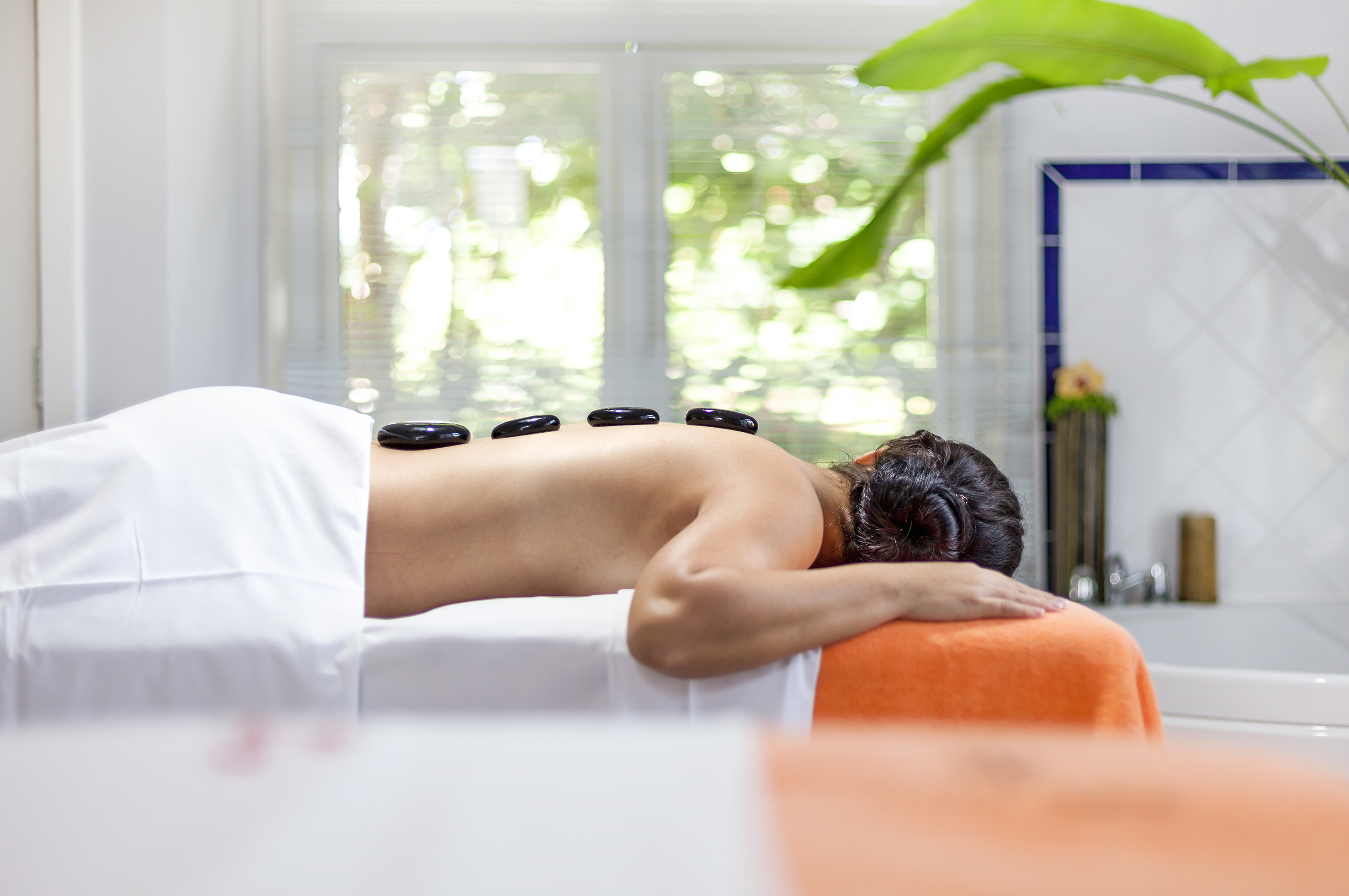 a woman lying on a bed with a stone on her back