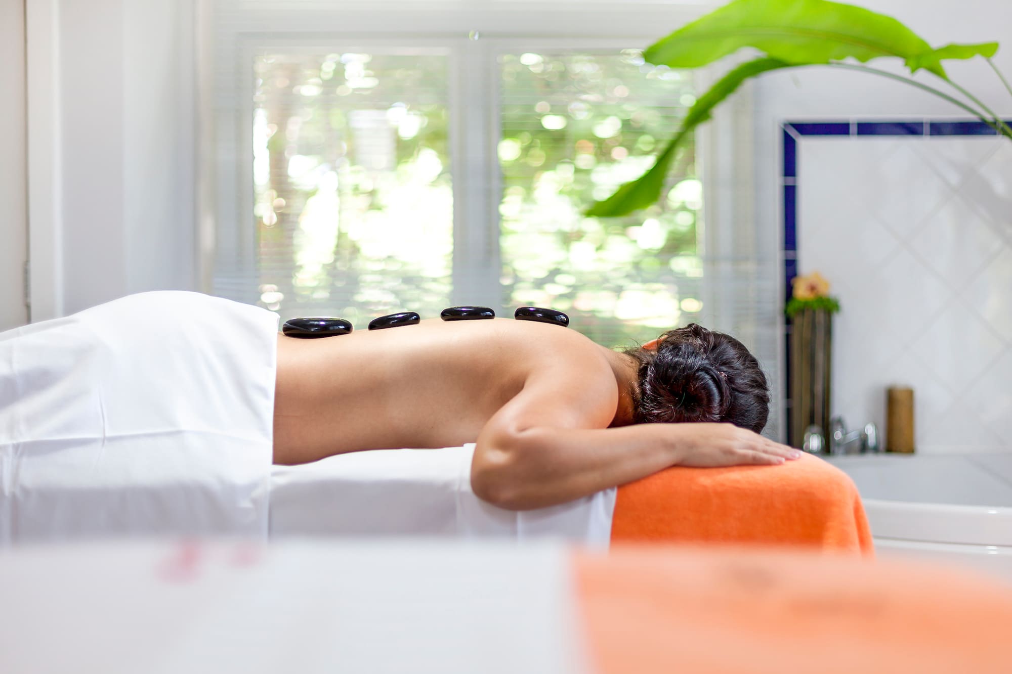 a woman lying on a bed with a stone on her back.