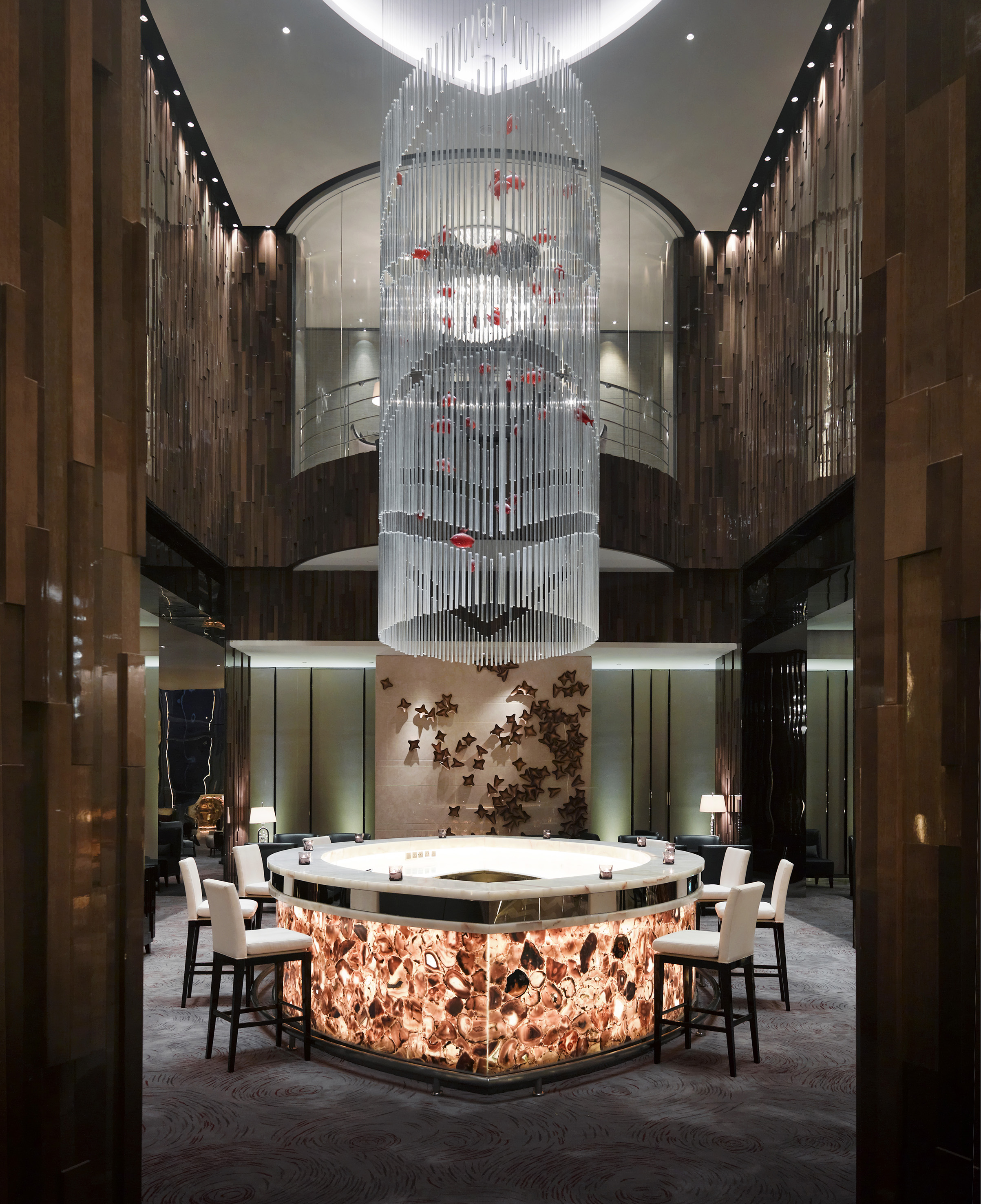 Luxury hotel bar with glowing agate counter and modern chandelier.