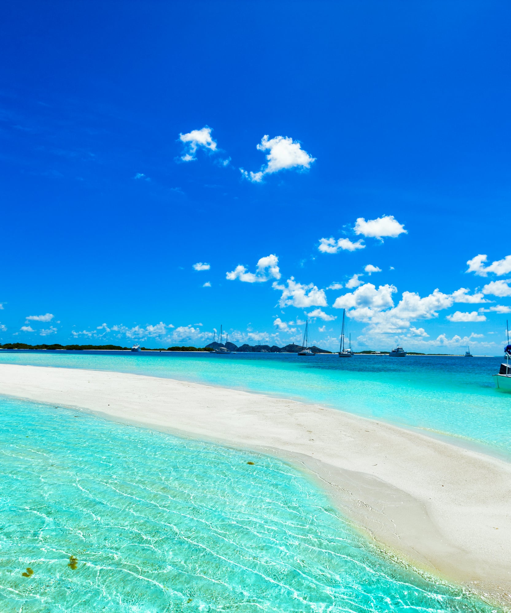Banco de arena blanca en aguas turquesas del Caribe con barcos.