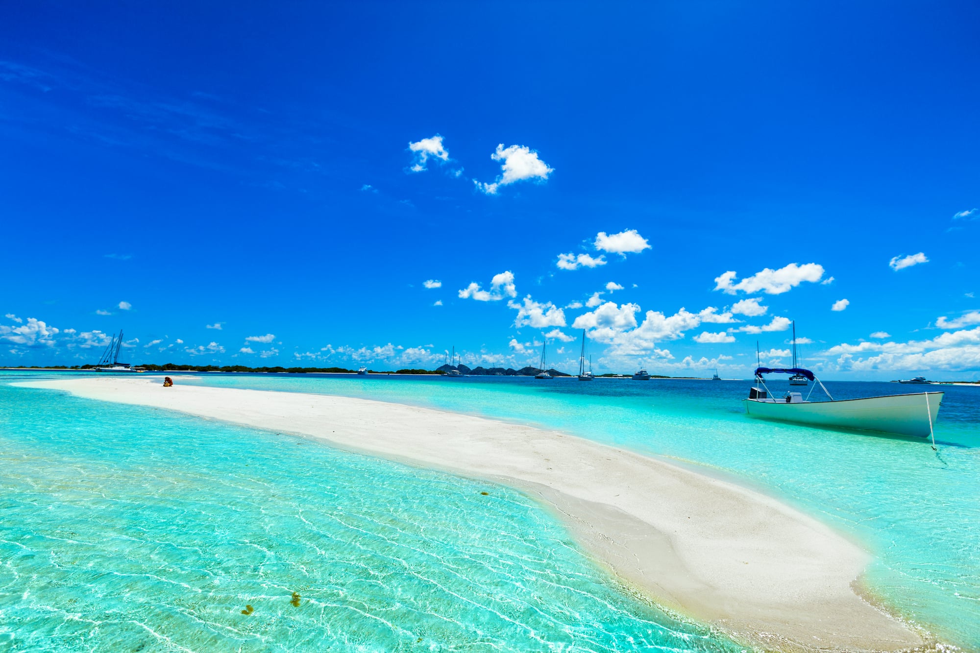 a white sand beach with a boat in the water