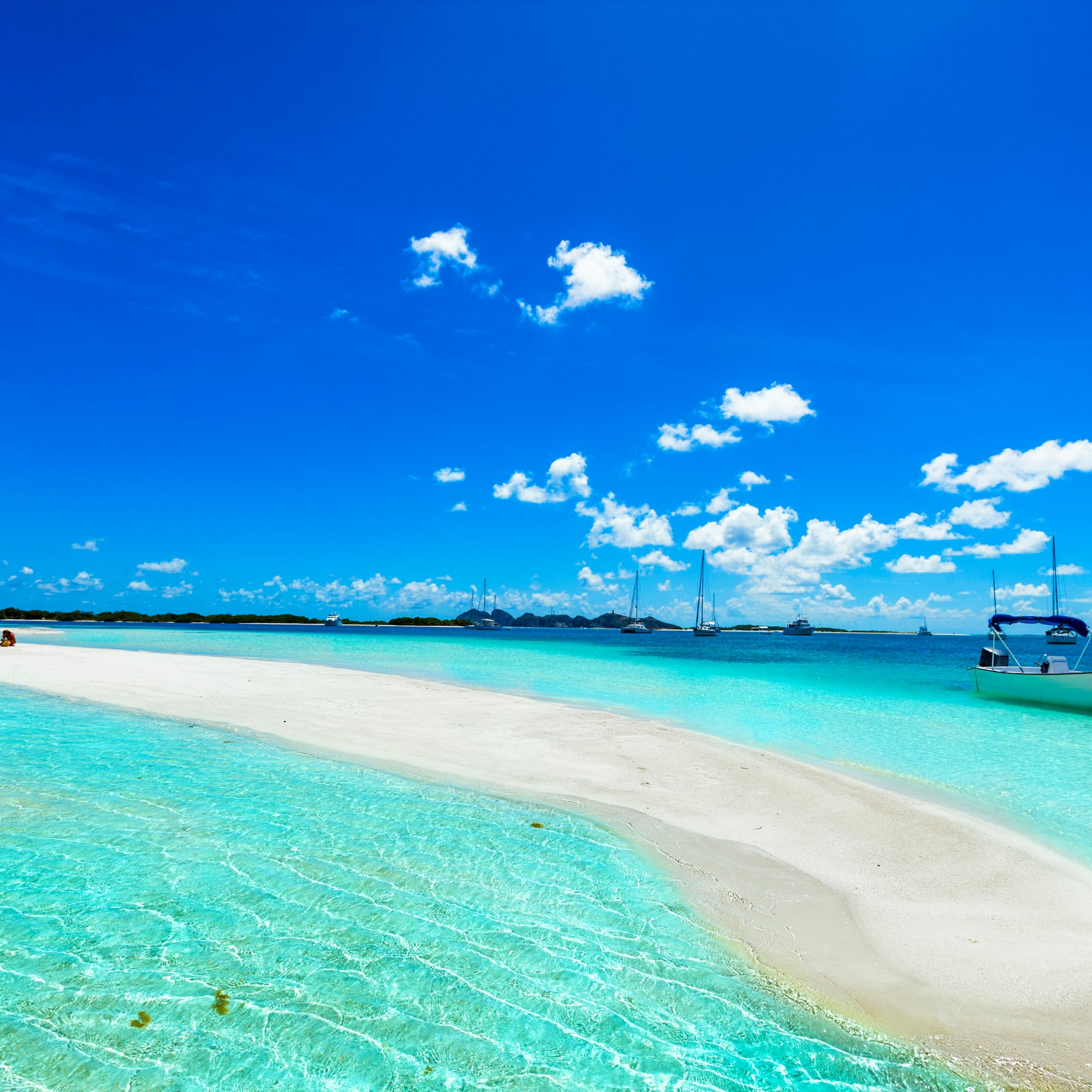 a white sand beach with a boat in the water