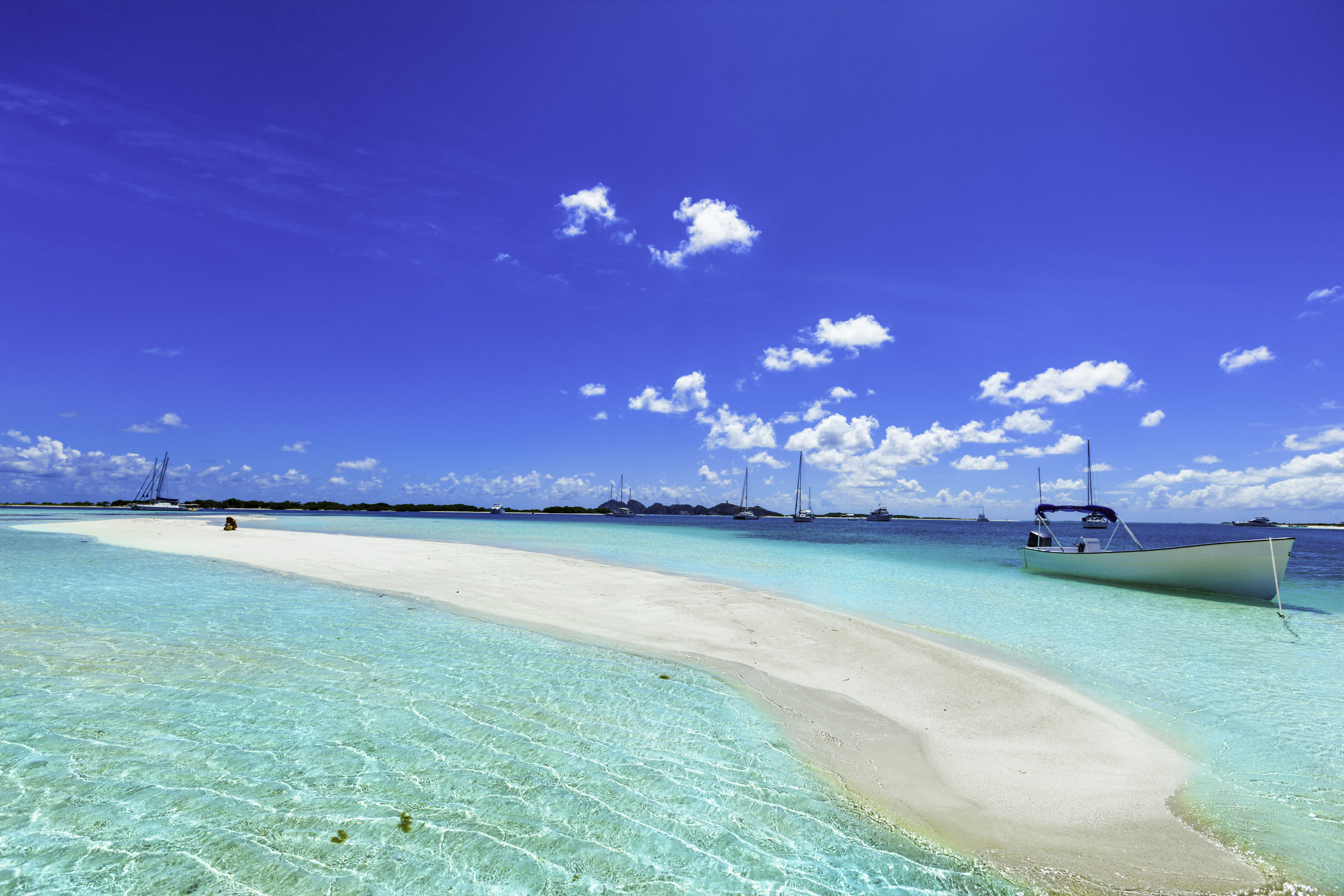 Banco de arena blanca en aguas turquesas del Caribe con barcos.