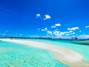 a white sand beach with a boat in the water