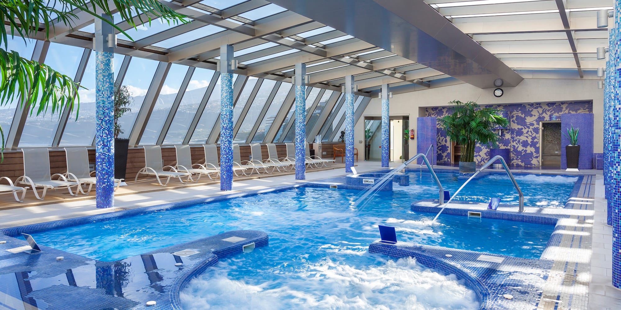 a large indoor pool with hot tubs and a glass roof