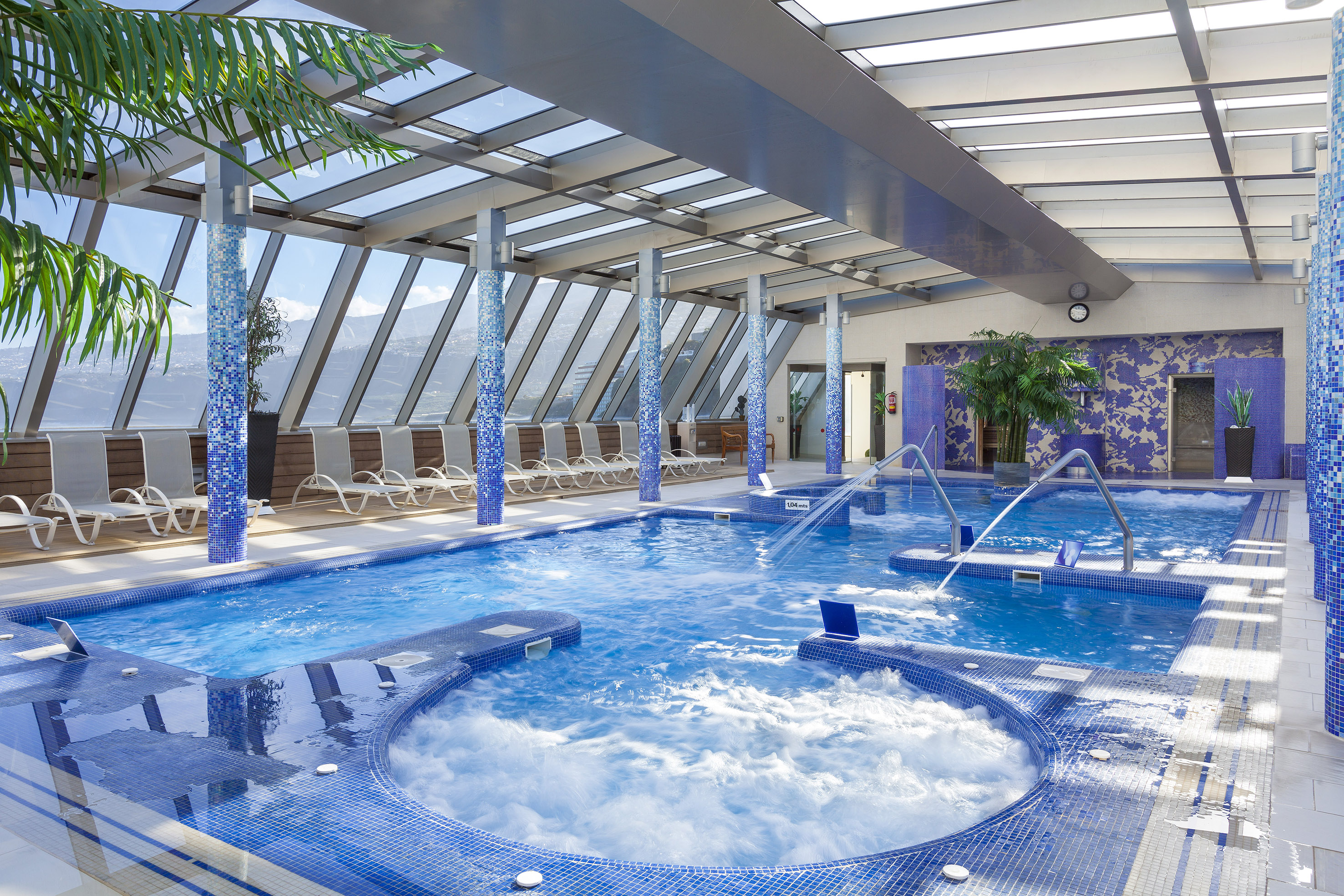 a large indoor pool with hot tubs and a glass roof