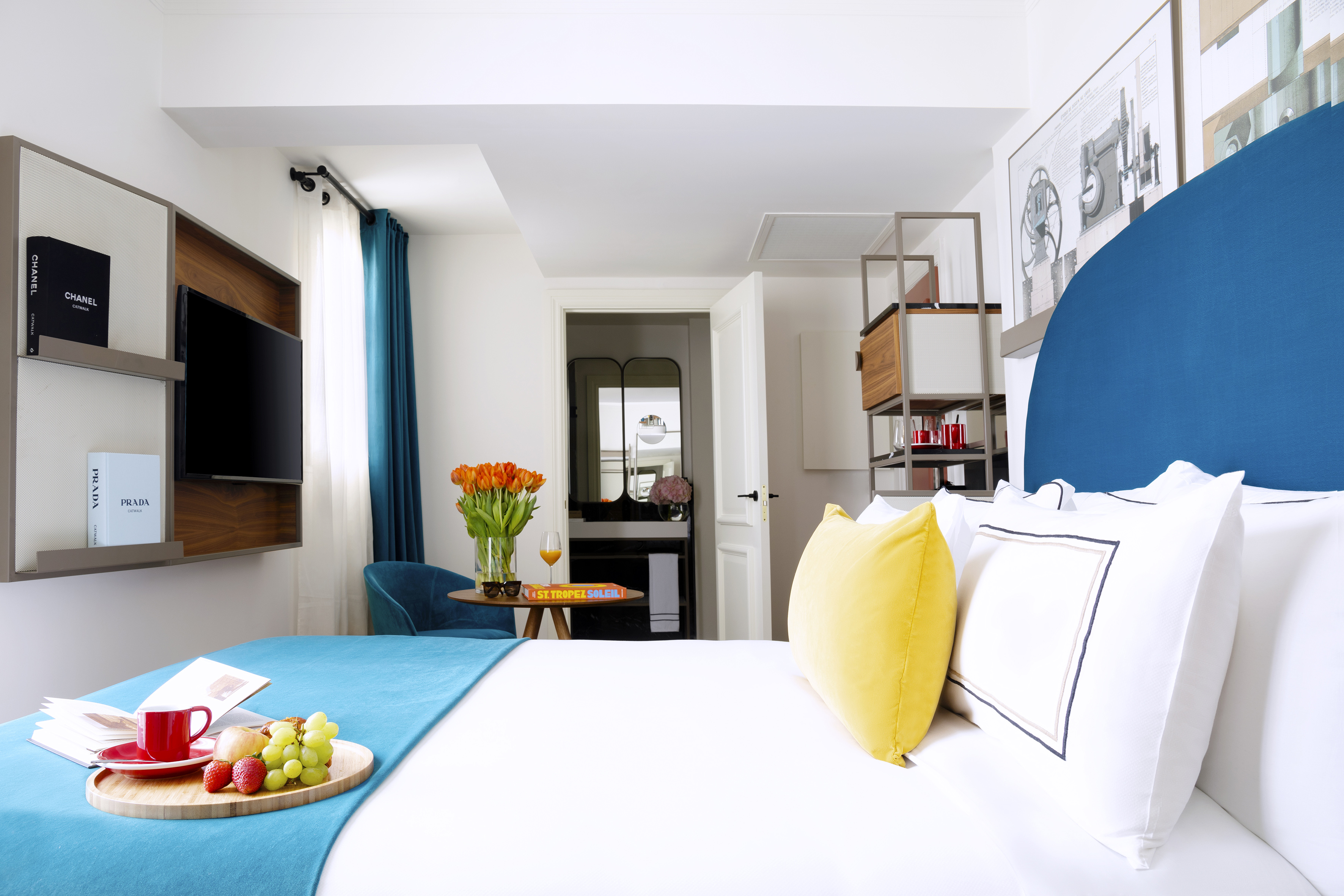 Stylish hotel room with white bed, blue accents, and a breakfast tray.
