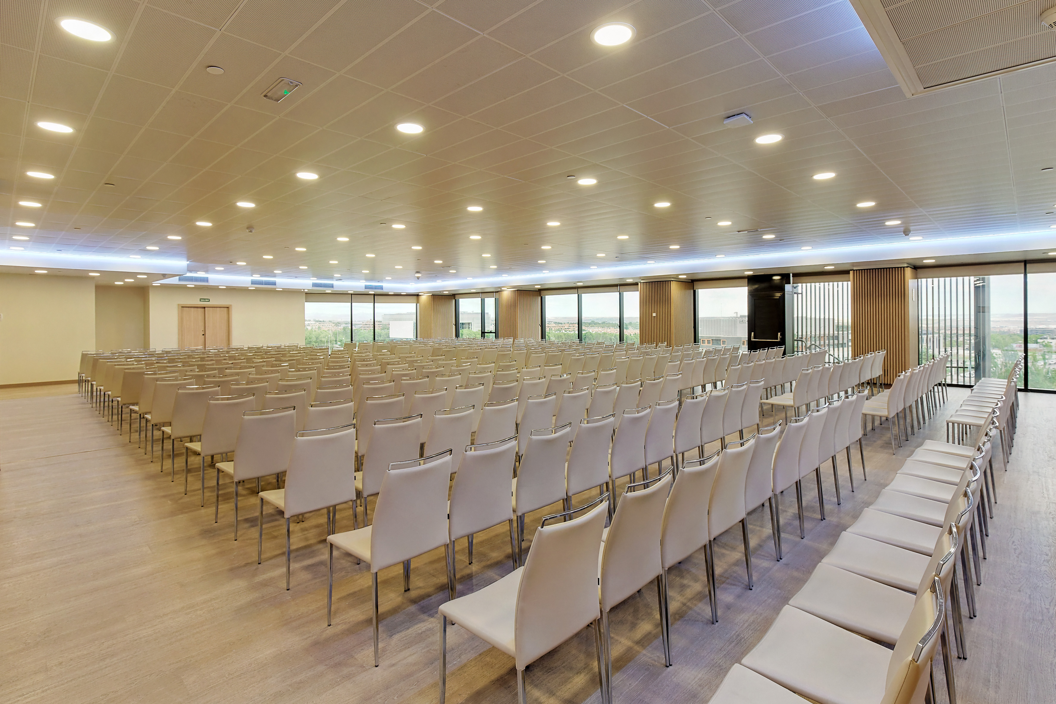 Spacious modern event hall with empty chairs and large windows.